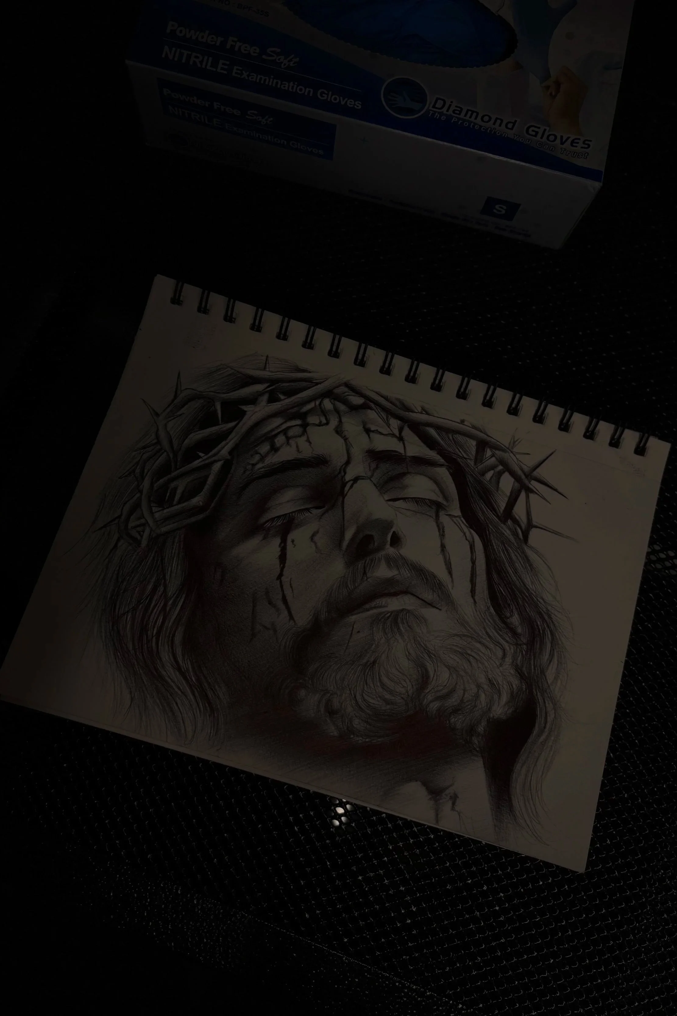 A sketch of a man's face with a crown of thorns, depicting Jesus Christ, drawn with black ink on paper.