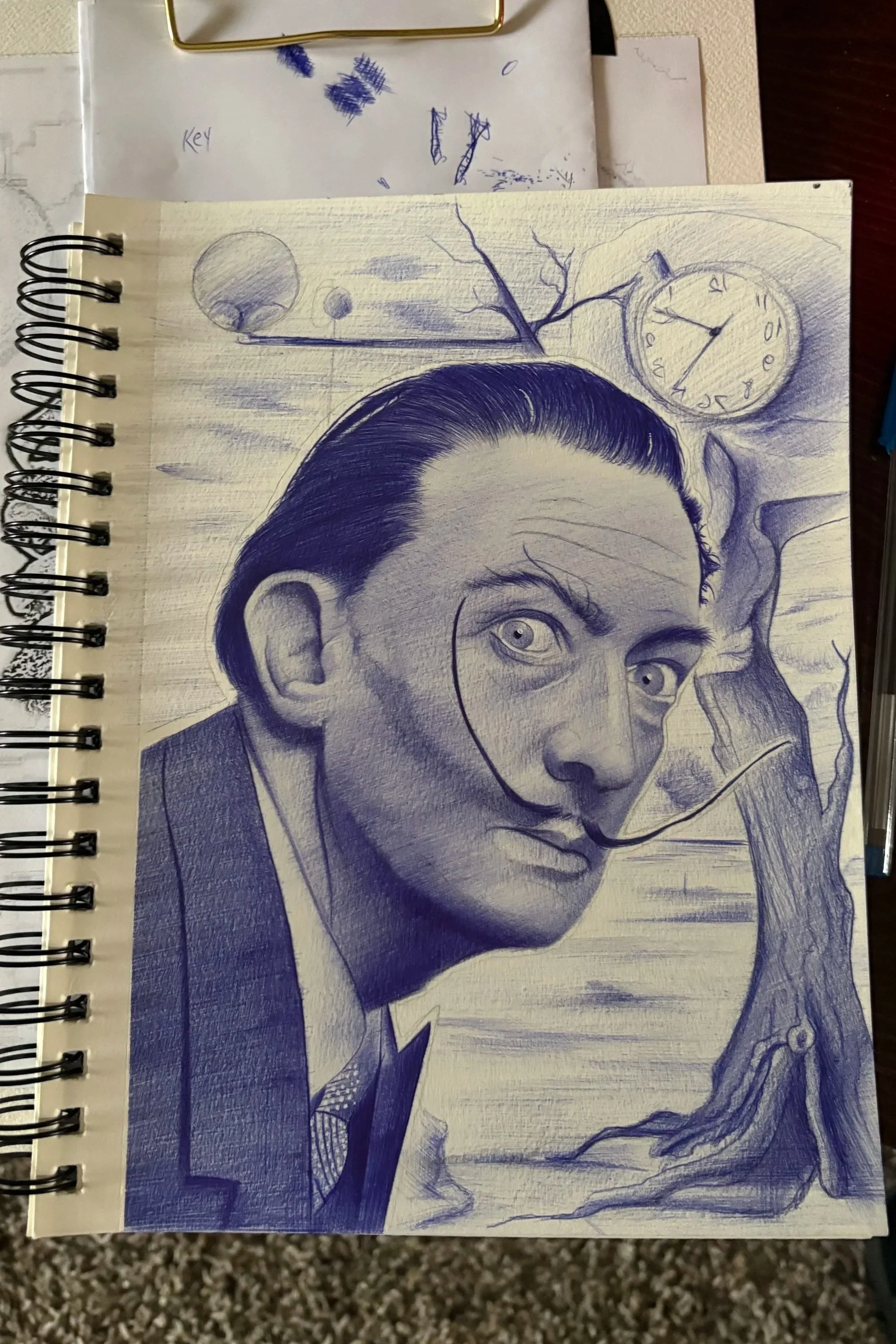 A blue sketch of a man with slicked-back hair, with a background featuring a clock, a tree branch, and abstract shapes, on a spiral-bound sketchbook page.