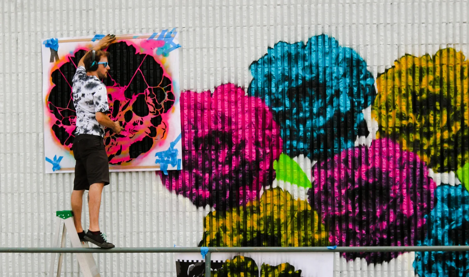 Alex Stewart standing in front of a finished festival mural.