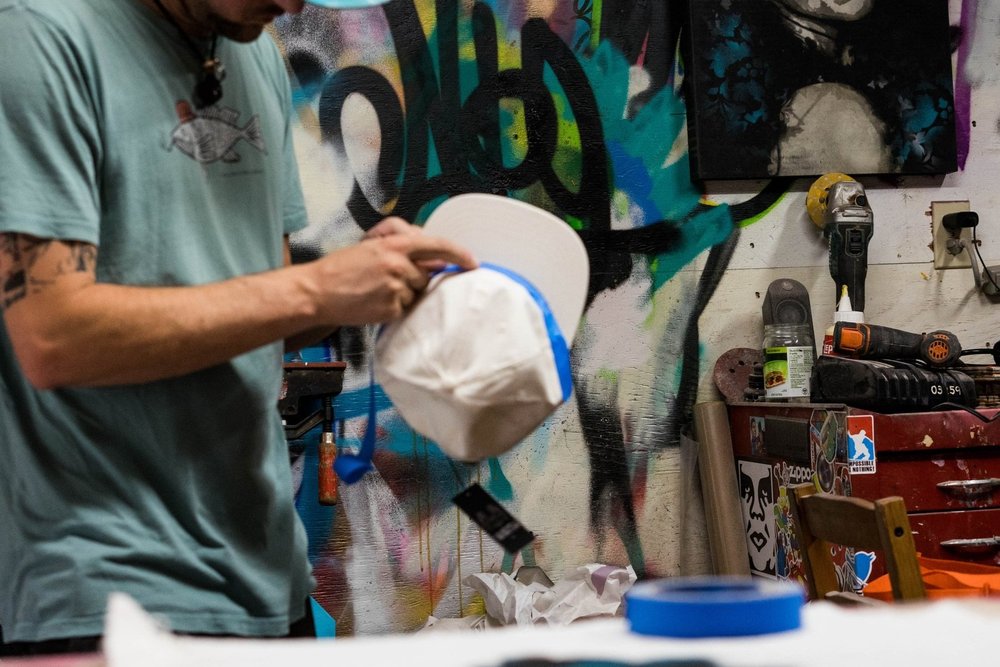 Alex Stewart hand-painting a hat in the studio.