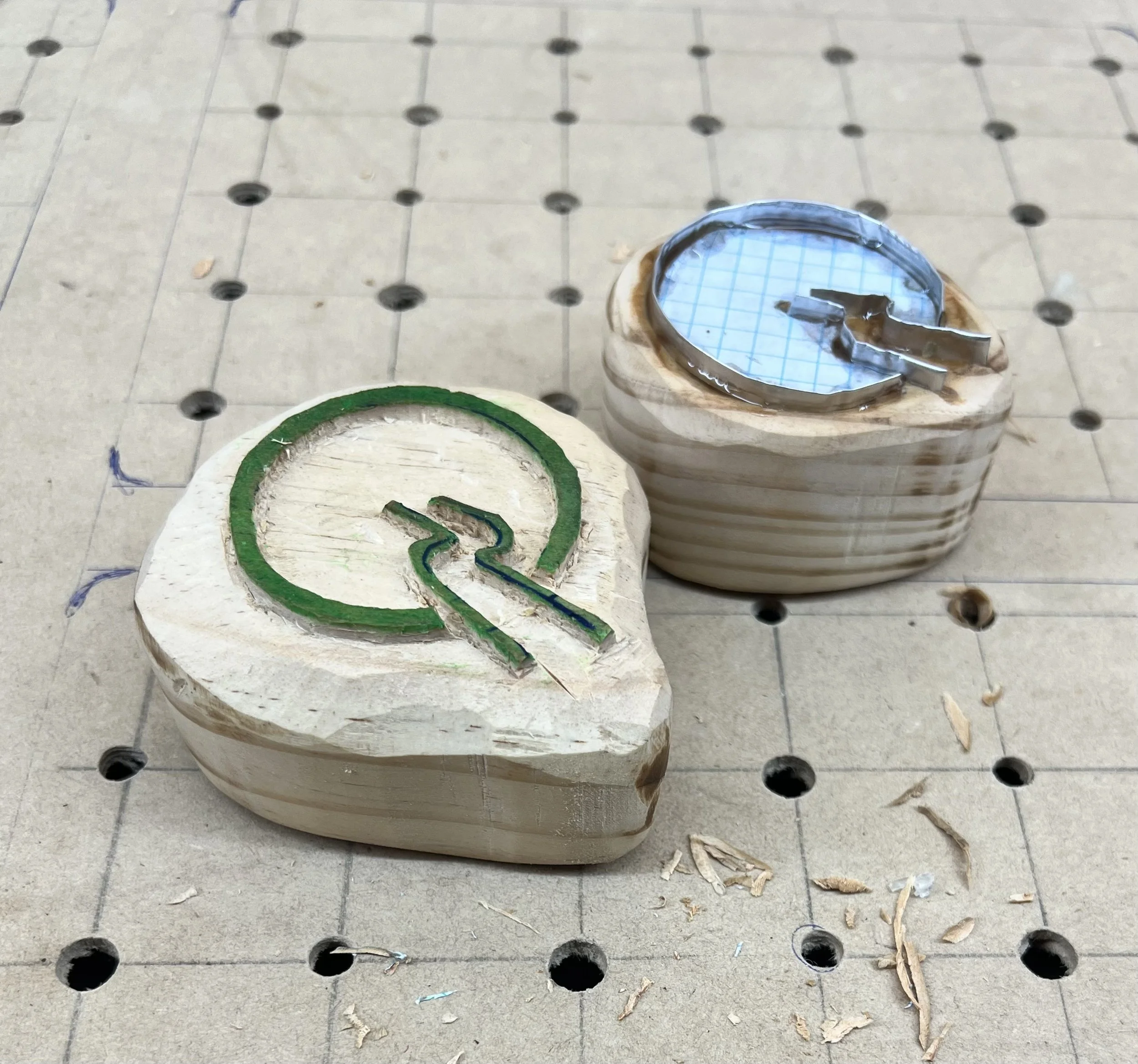 Two wooden stamps, carved with the Insightful Path logo, one of wood, and one of aluminium.