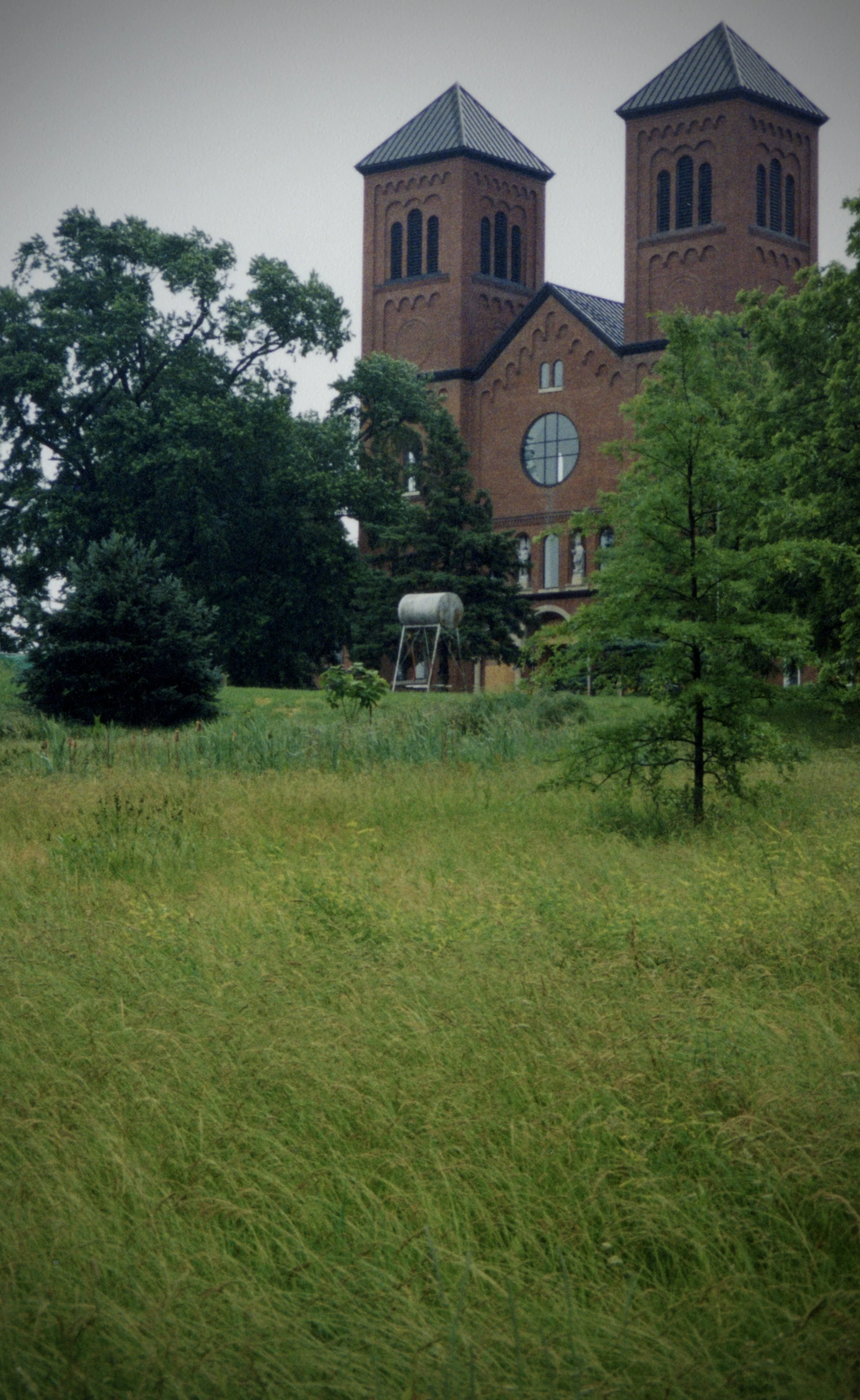 Red brick Benedictine monastery surrounded by tall summer grass in rural Missouri during sunset.