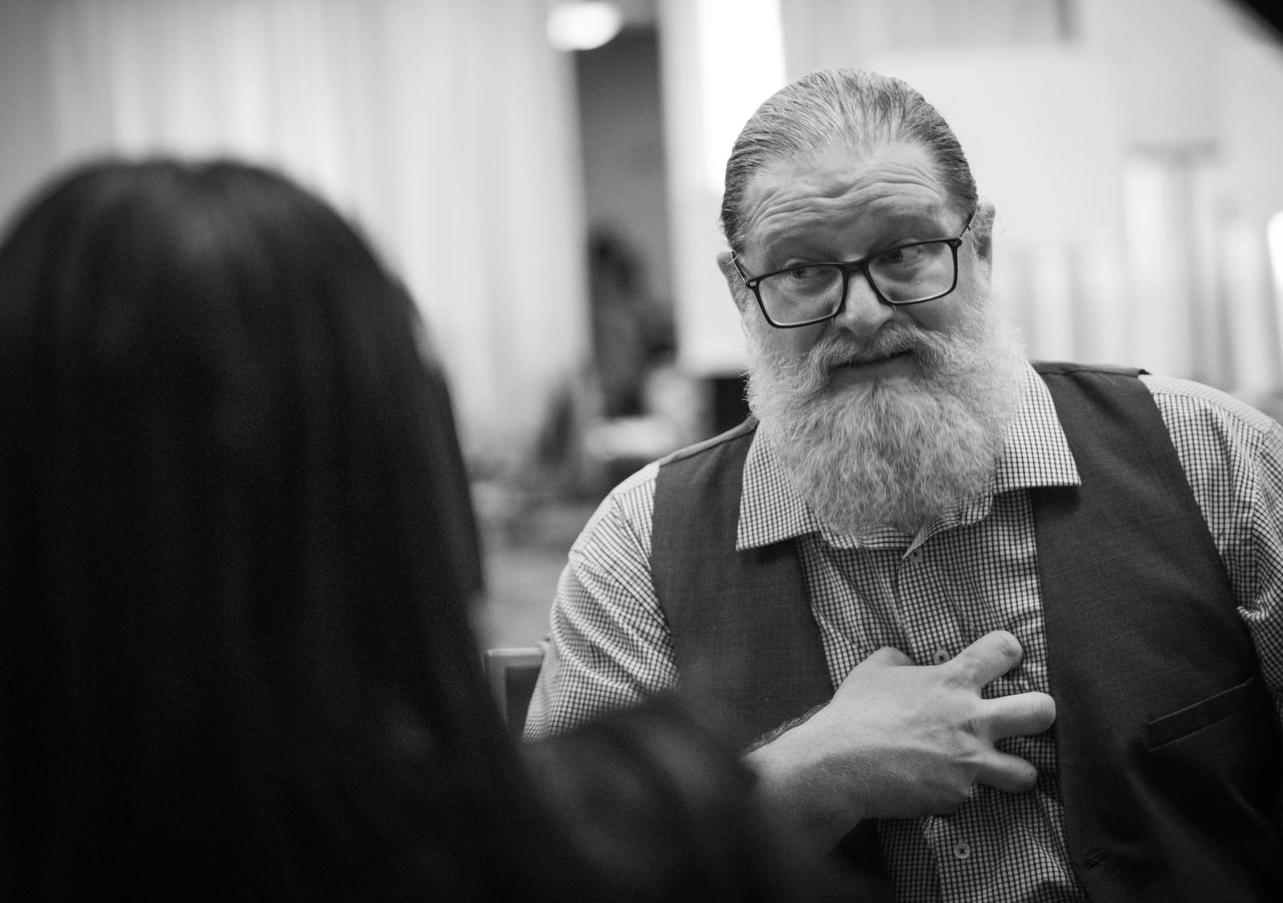 James Samana in conversation with another facilitator, hand placed over his chest, expressing presence and care during a values-based discussion.