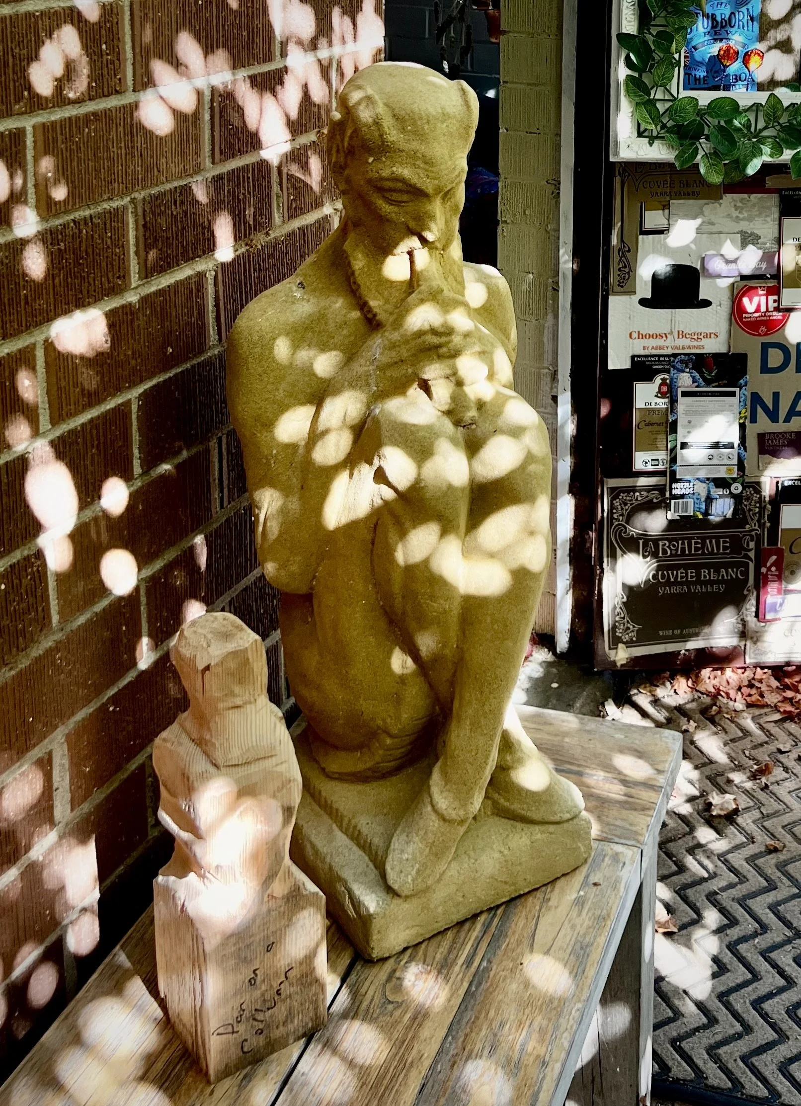 Stone Art Nouveau Pan statue and an unfinished cedar wood Pan sculpture sitting side by side at the entrance to my studio.