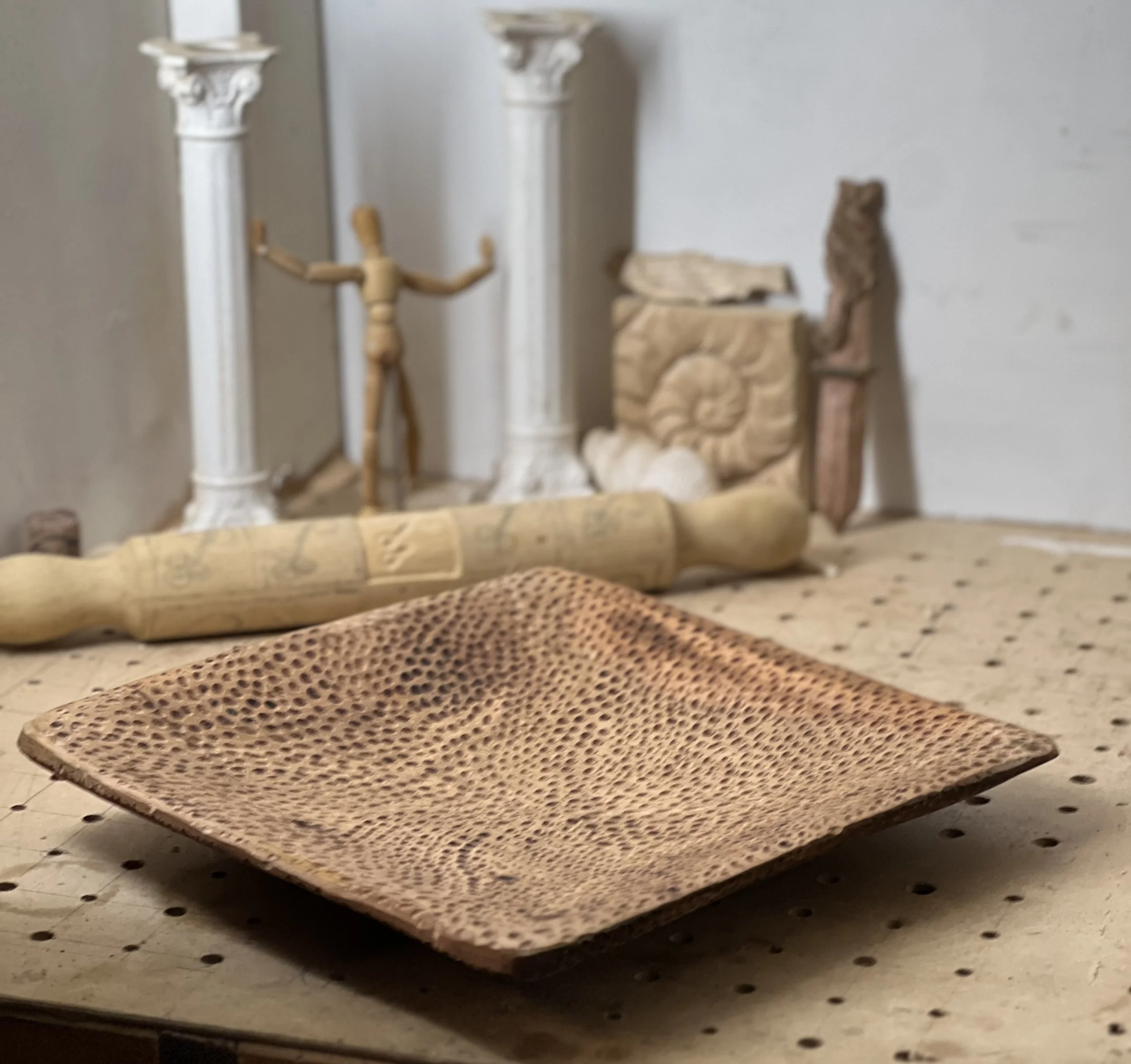 Close view of the curved, dimpled chisel marks radiating across the surface of a hand-carved wooden plate.
