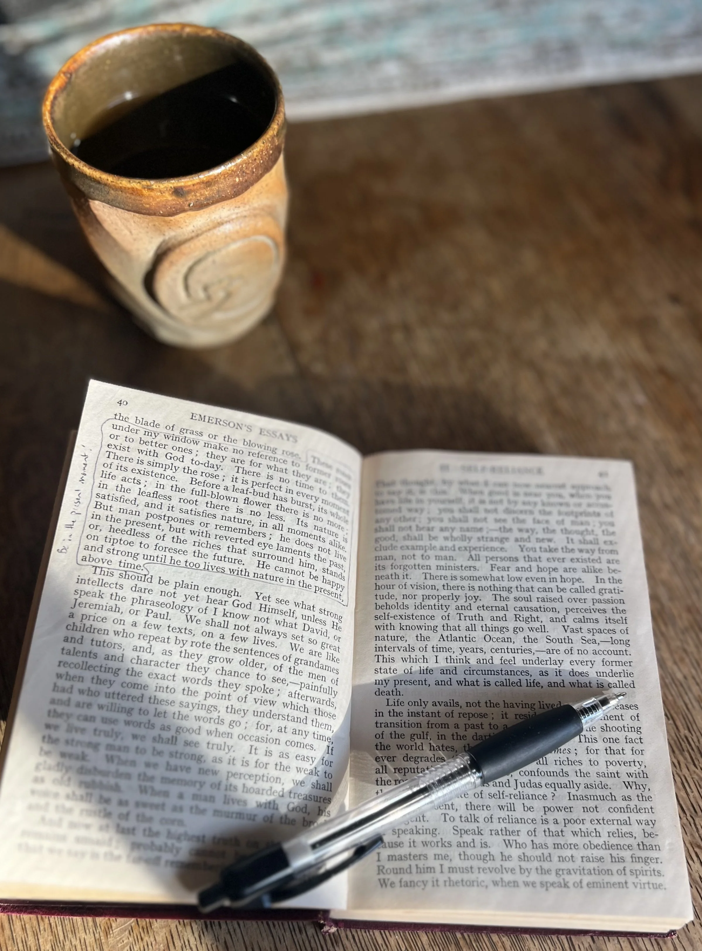 Emerson essay on self-reliance open to passage about living in the present like a rose, teacup in background