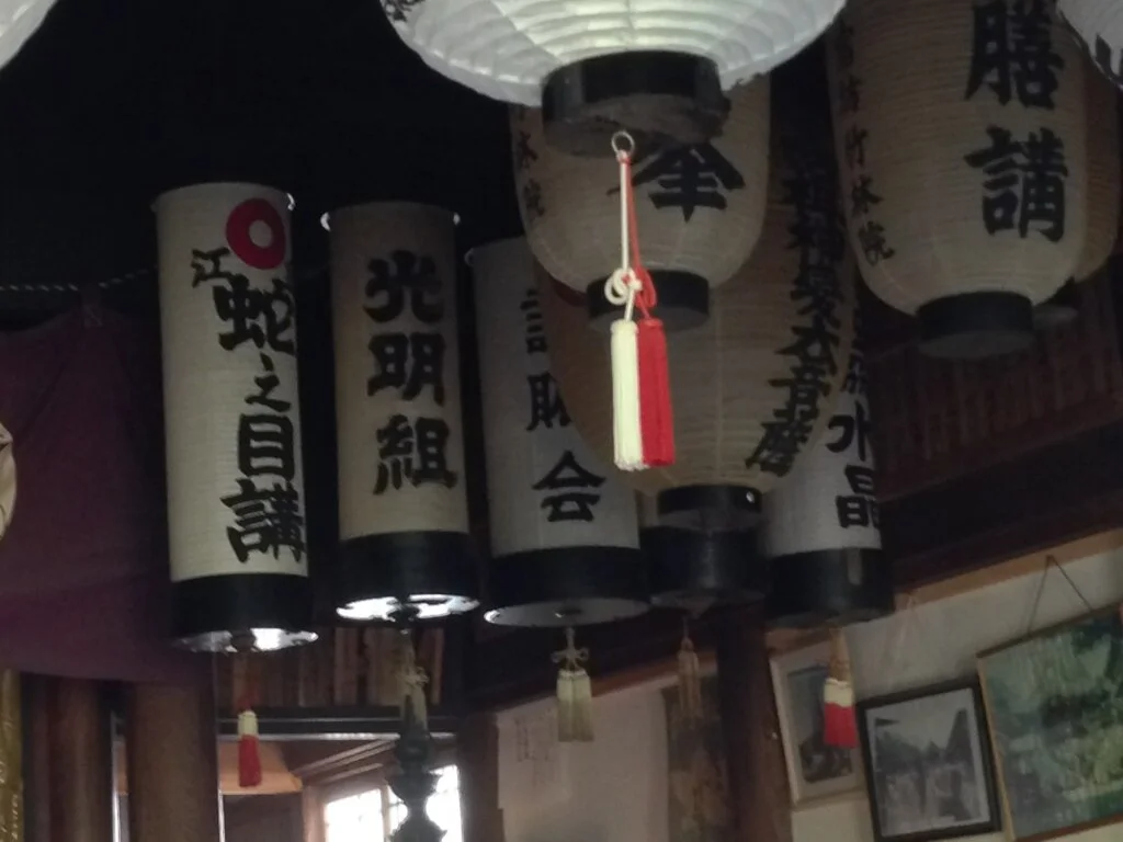 Traditional Japanese paper lanterns hanging from ceiling, with Japanese characters written on them.