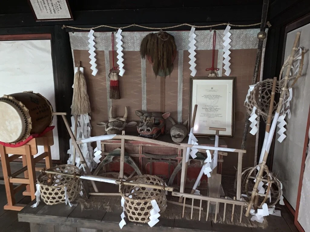 Decorative display of traditional Japanese cultural items, including a drum, a wooden cart, masks, and paper streamers
