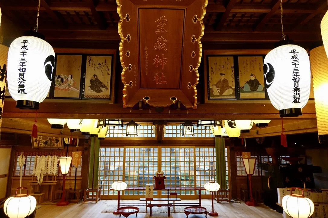 Interior of a traditional Japanese temple decorated with paper lanterns, paintings, and wooden carvings.