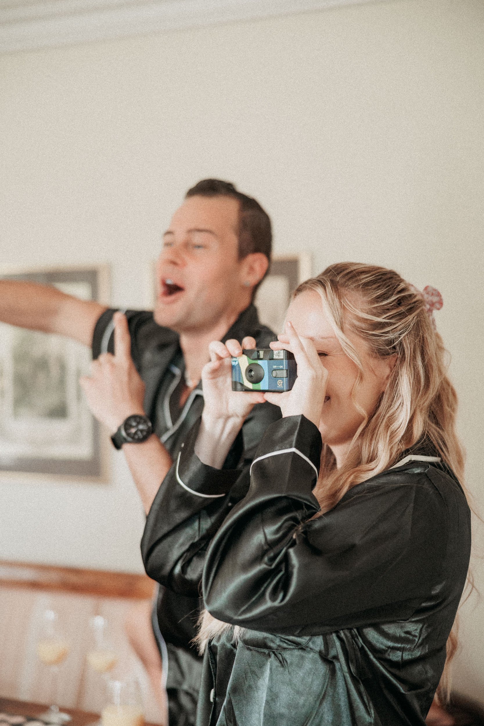 En kvinna fotograferar med en kamera medan en man skrattar och pekar.