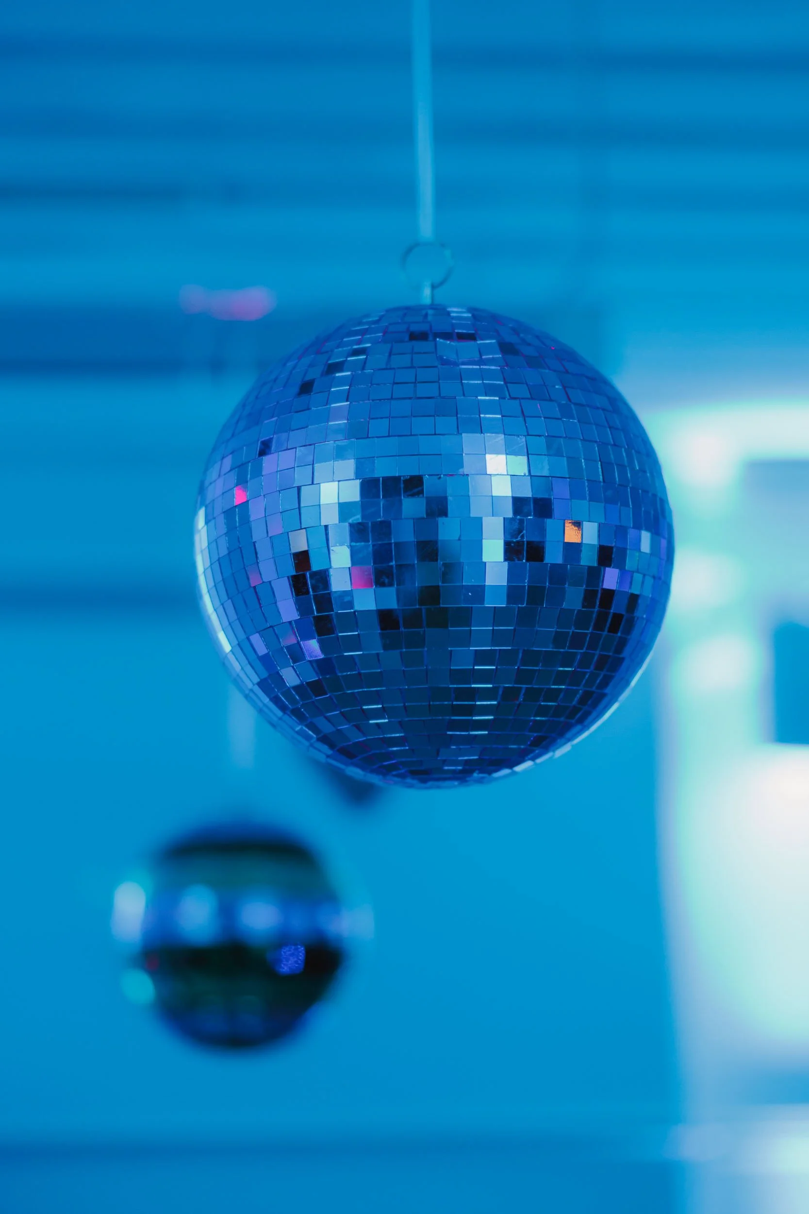 En stor diskokula med små spegelklädda ytor hänger i taket, med en blå belysning i bakgrunden.