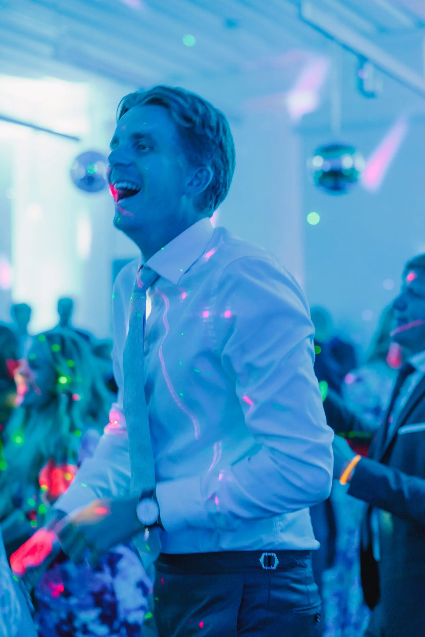 Ung man som dansar på fest med laserljus och musik i bakgrunden.