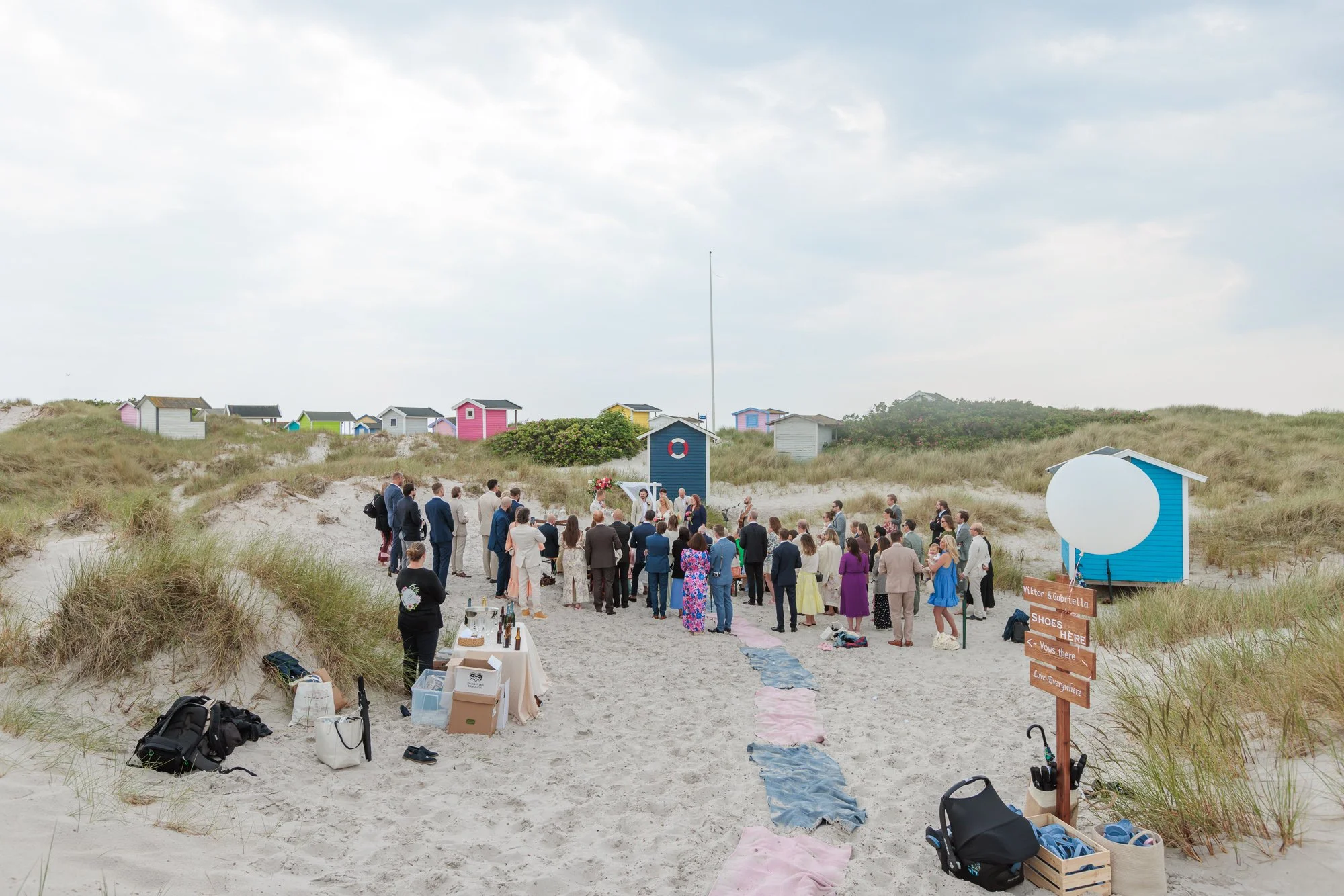 Vigsel på strand med färgglada badhytter och sanddyner, södra Sverige