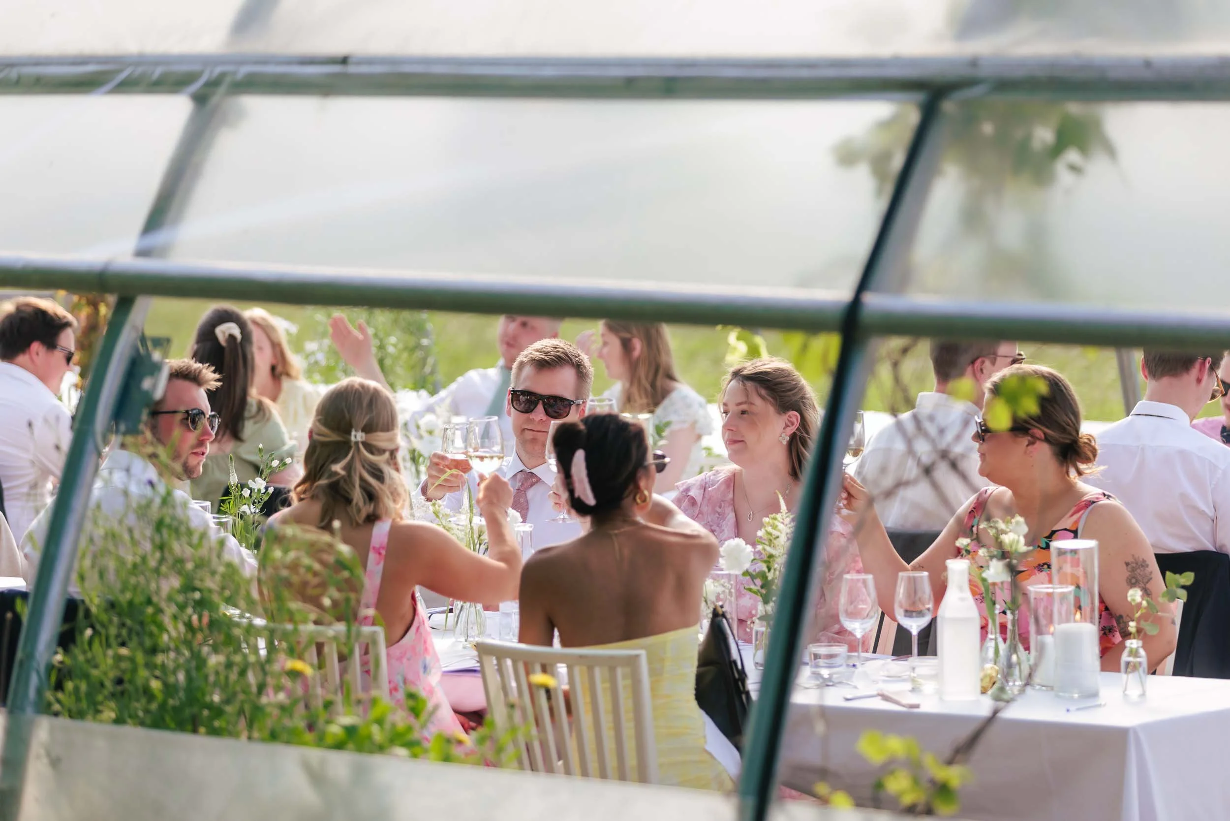 Bröllopsgäster skålar vid dukat bord utomhus – bröllopsmiddag Sverige