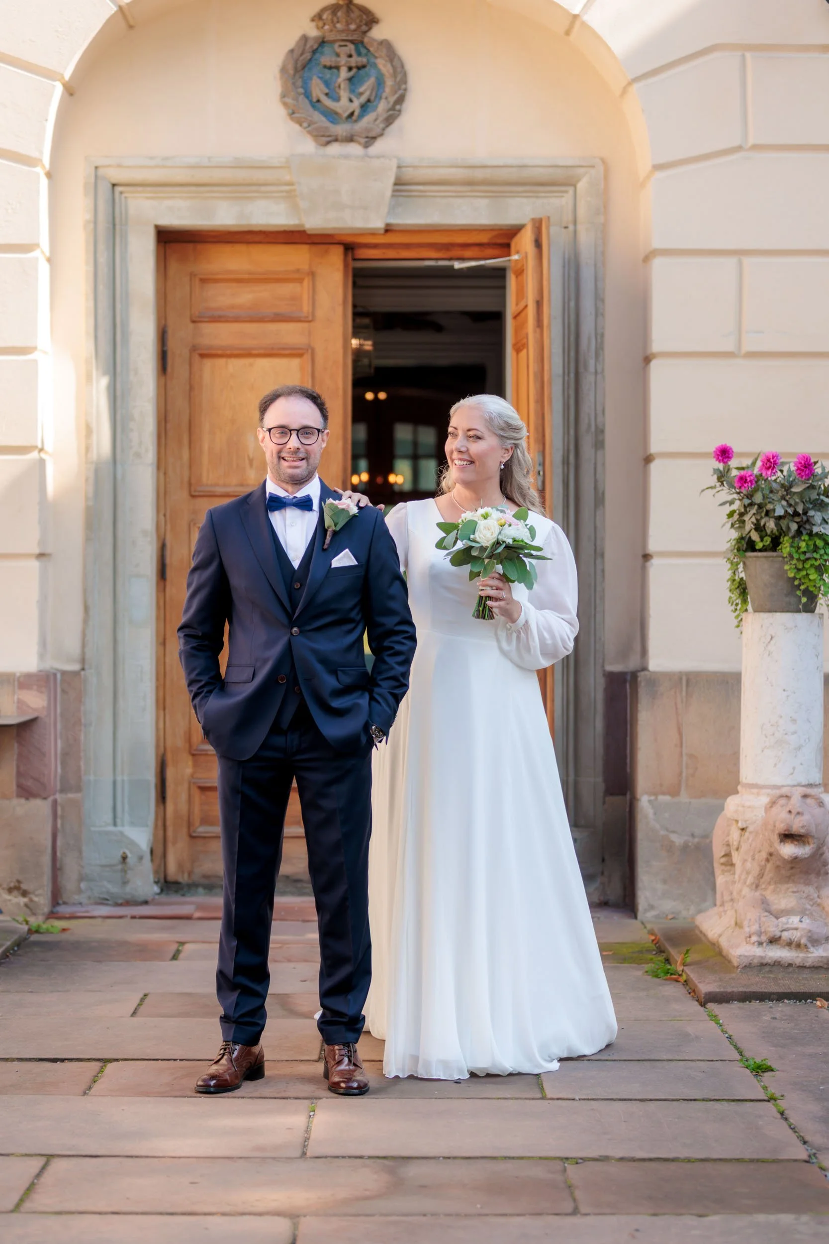 En brud och en brudgömma står framför en dubbar dörr med en okänd symbol ovanför.