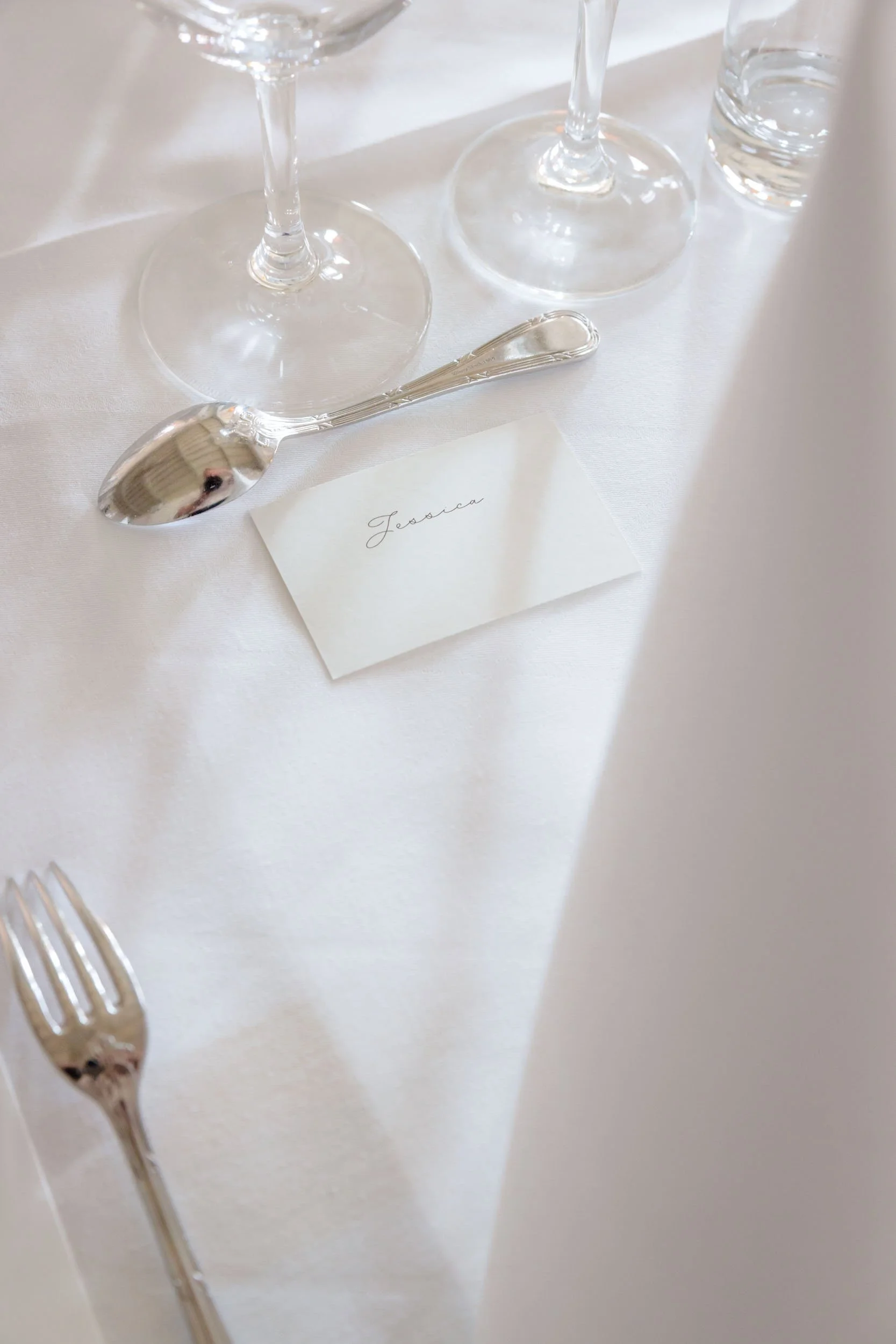En vit dukad matplats med whiskeyglas, en liten pall, en liten sked och en namnlapp med texten 'Jessica'.