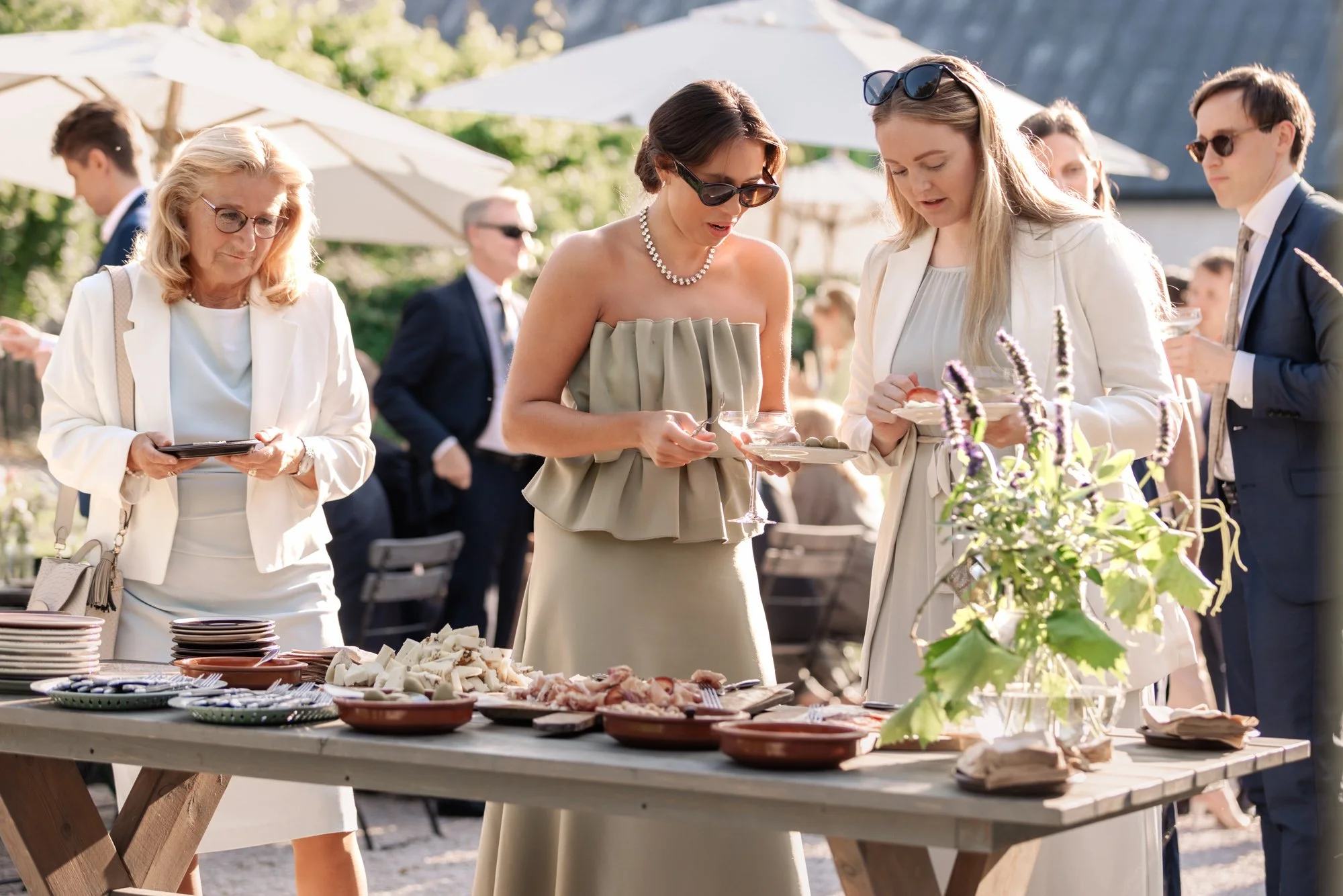 Bröllopsgäster vid mingelbuffé utomhus i solen – litet bröllop mat och mingel Sverige