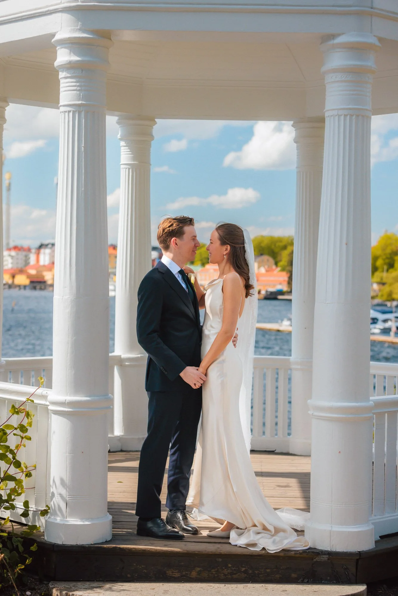 Bröllopspar i vit paviljong vid vattnet på Waldemarsudde – bröllopsfoto Stockholm