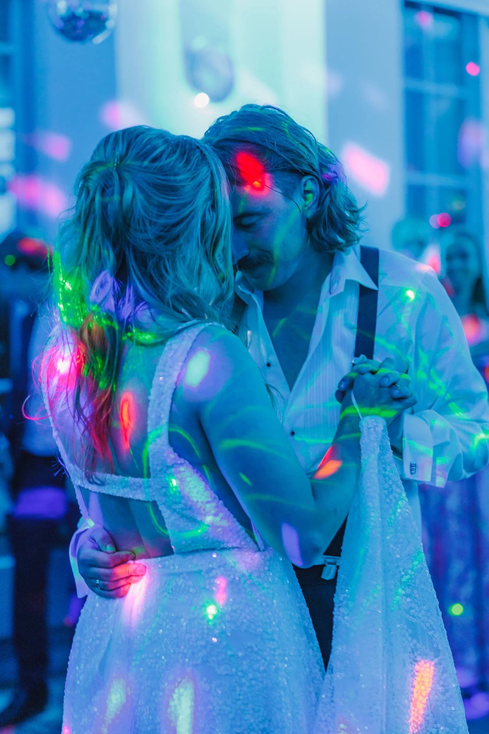 Ett par dansar parar sig i en färgglad, neonpysande miljö.