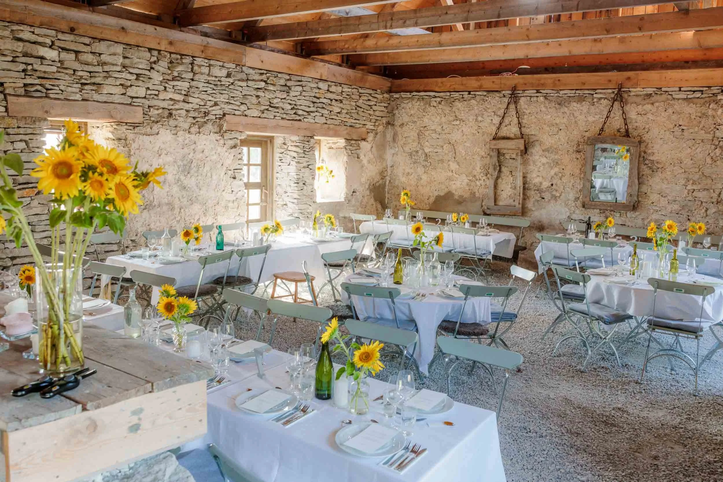 Wedding dinner set in a rustic barn with stone walls and wooden beams