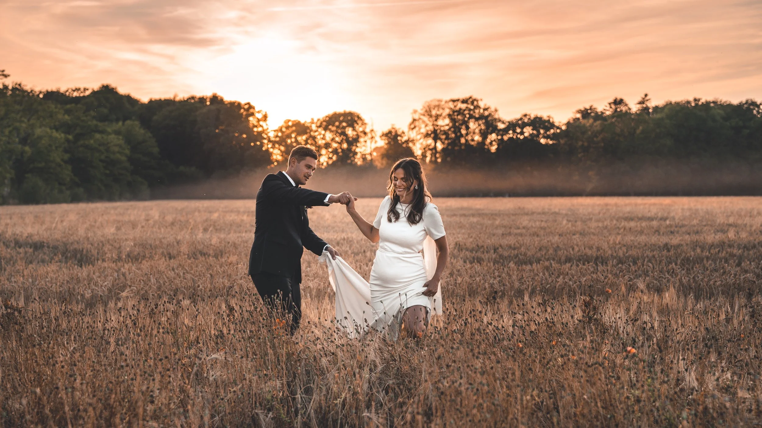 A bride and groom are photographed at sunset in an open landscape on their wedding day
