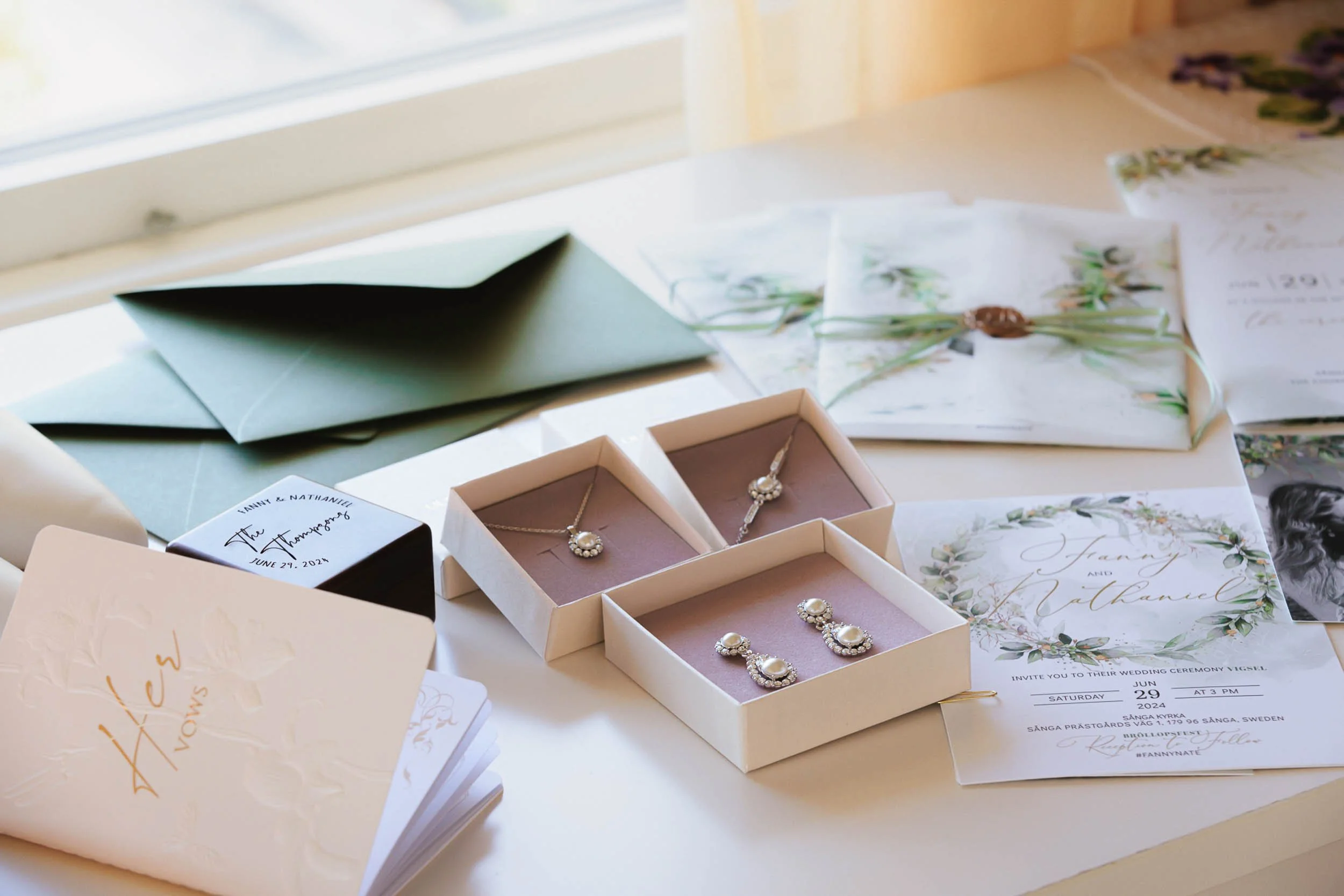 Bröllopsinbjudningar, ringar och vykort på ett bord.