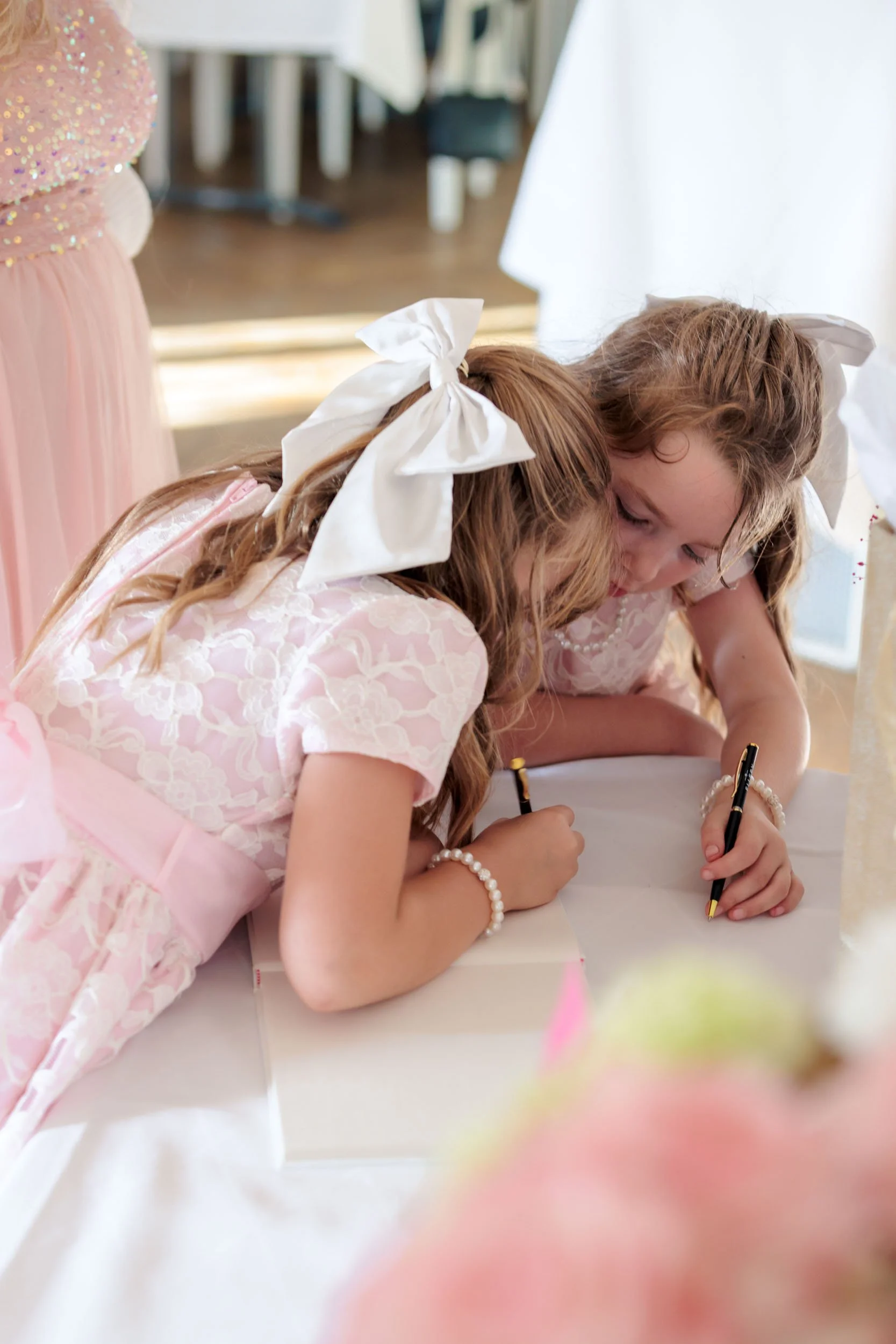 Två unga flickor skriver på ett bord, troligen under ett firande eller. 