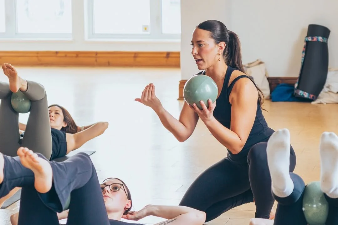 A yoga instructor holding a yoga ball during a class