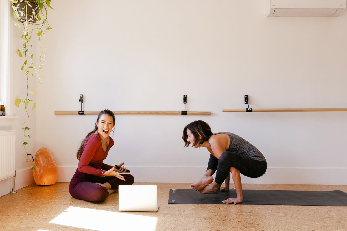 Catalina, CEO of Telomere, laughing while Melissa, COO, is doing a Crow Pose, also known as Kakasana or Bakasana