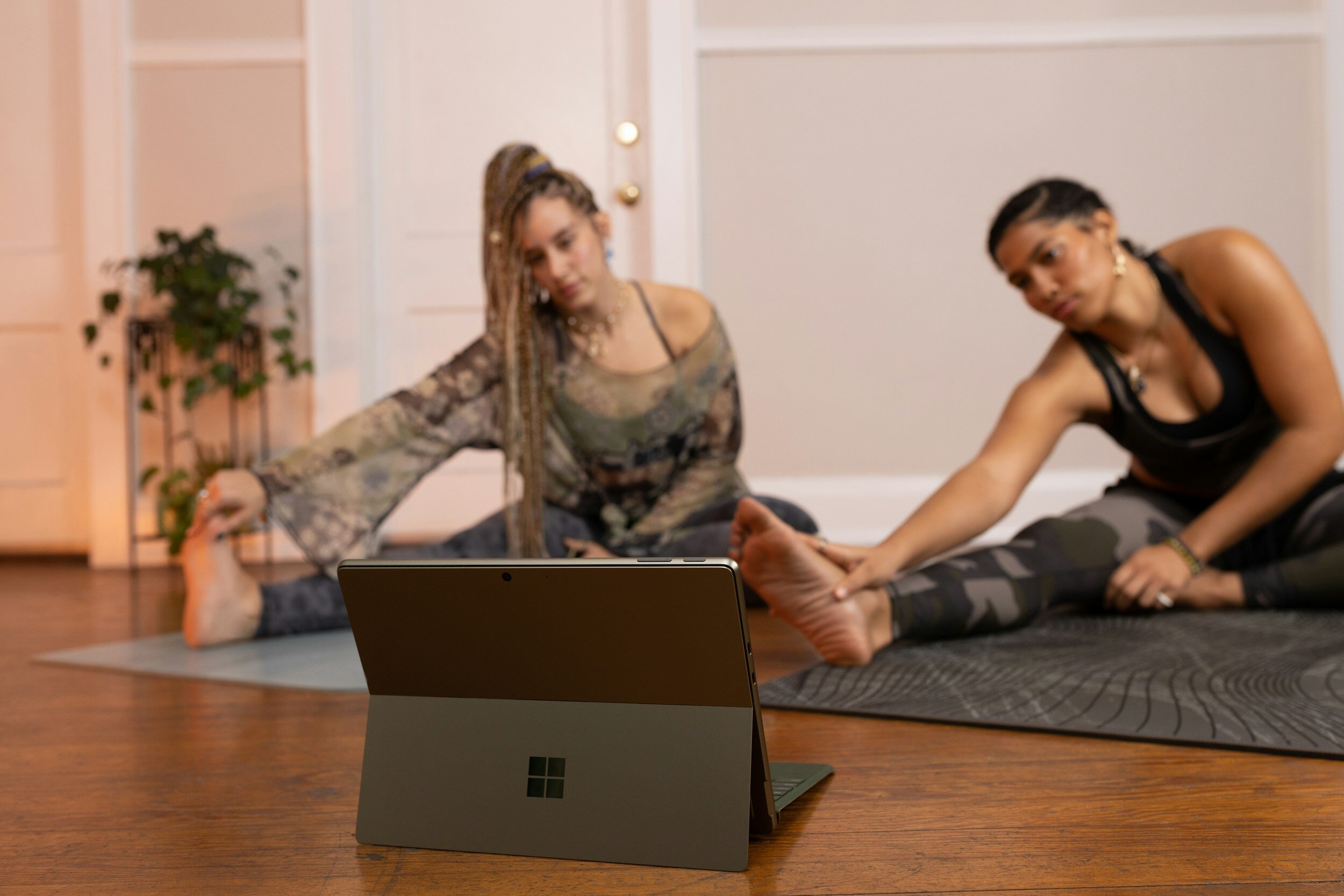 Two women doing their yoga stretching and workout from home with a laptop