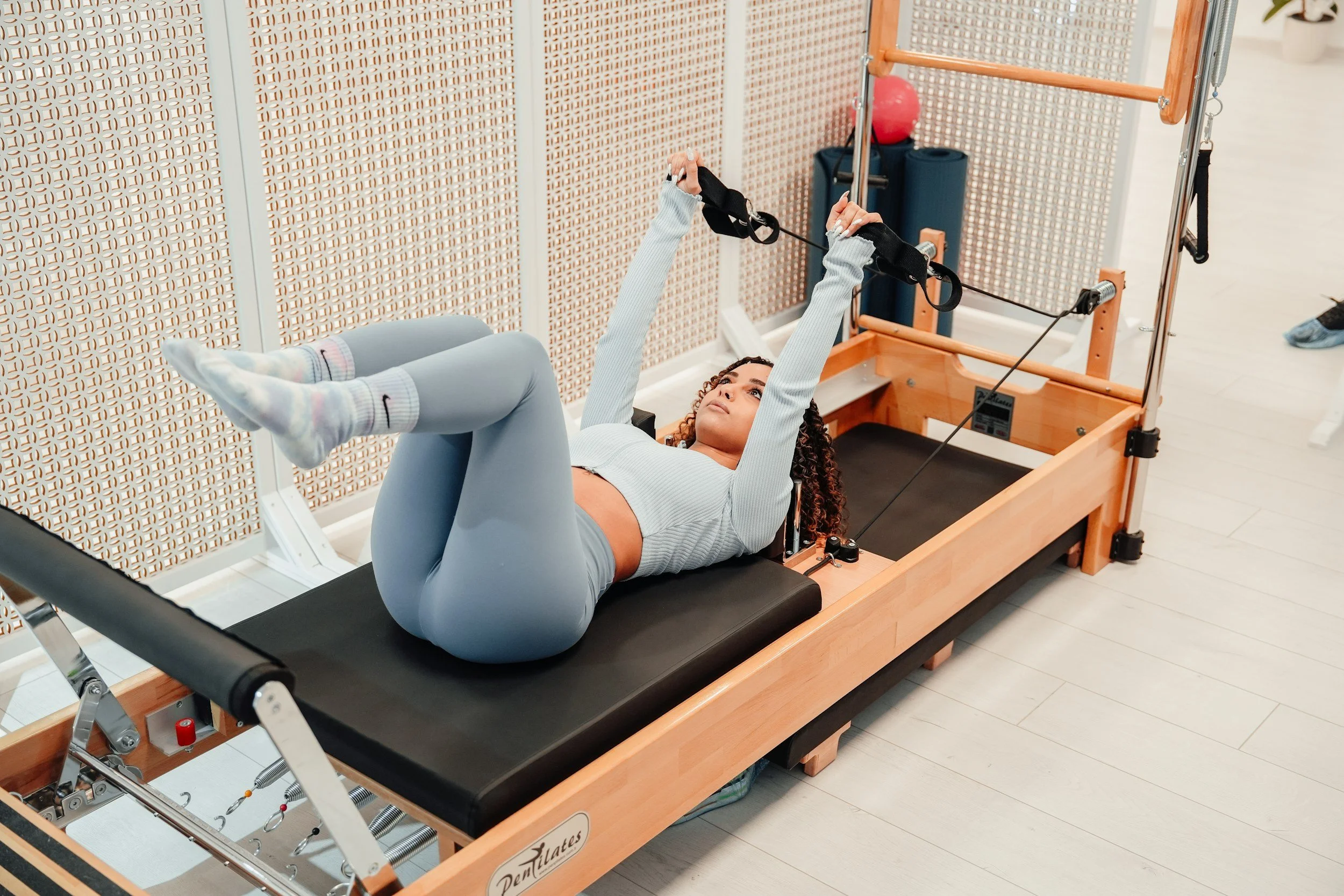 A woman in a matching workout outfit doing Pilates in a reformer