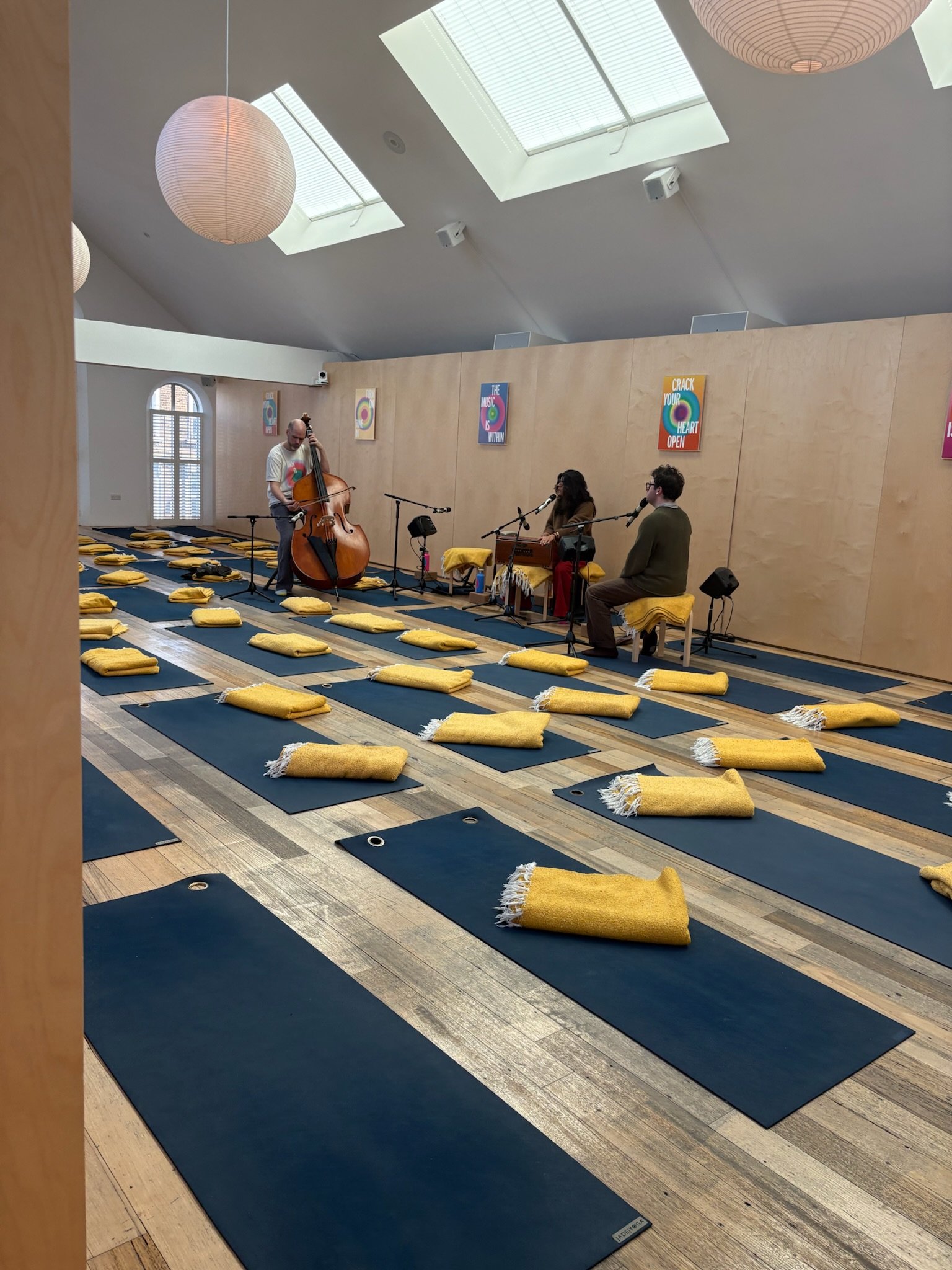 Yoga mats and blankets on the floor of a studio with musical instruments on the front