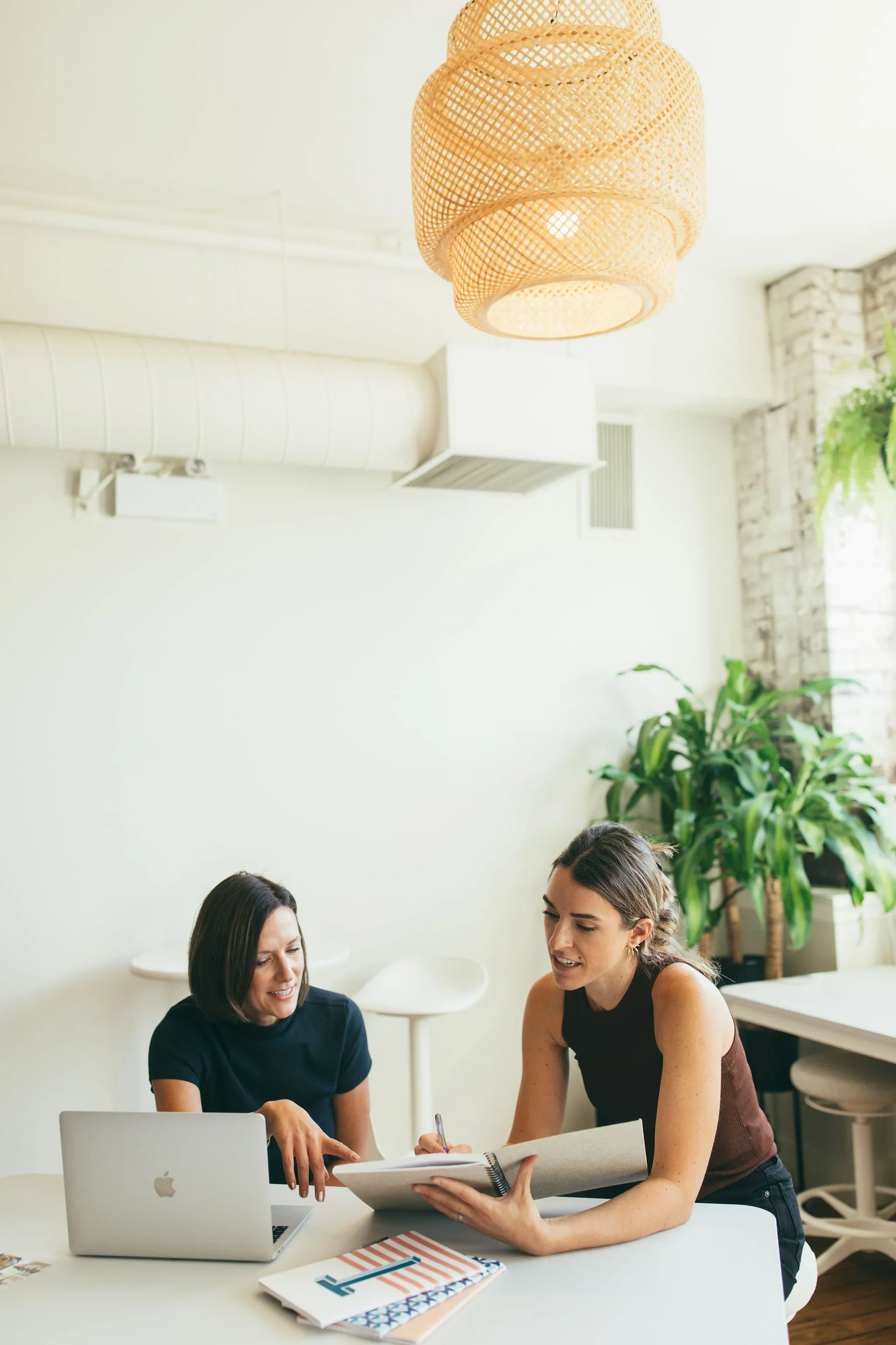 Catalina and Melissa consult an open notebook