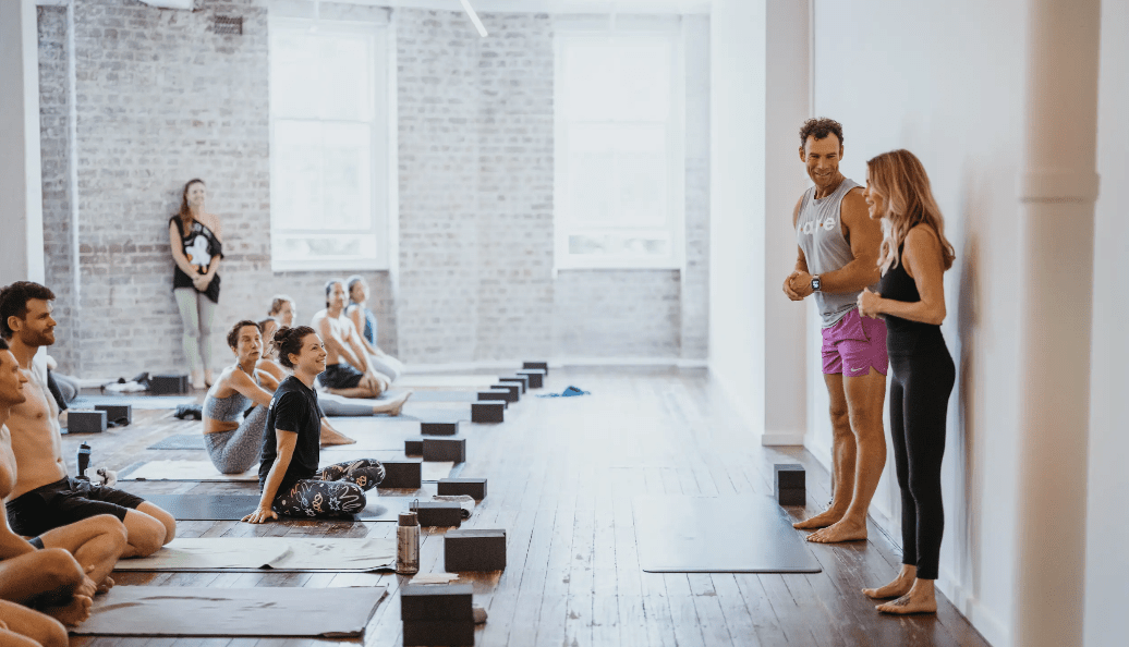 Two yoga instructors stand before an audience