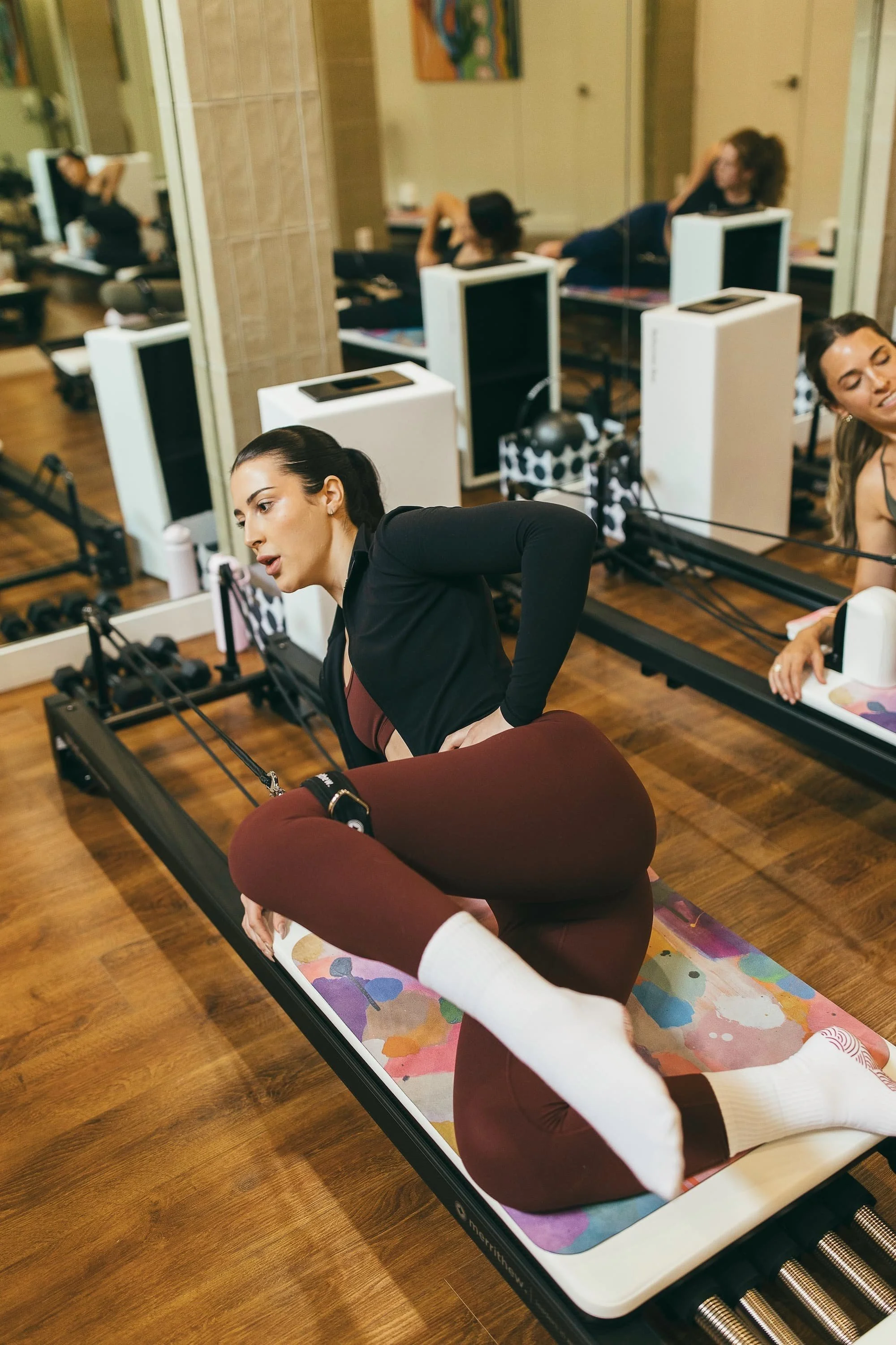 A woman does pilates exercises on a reformer machine