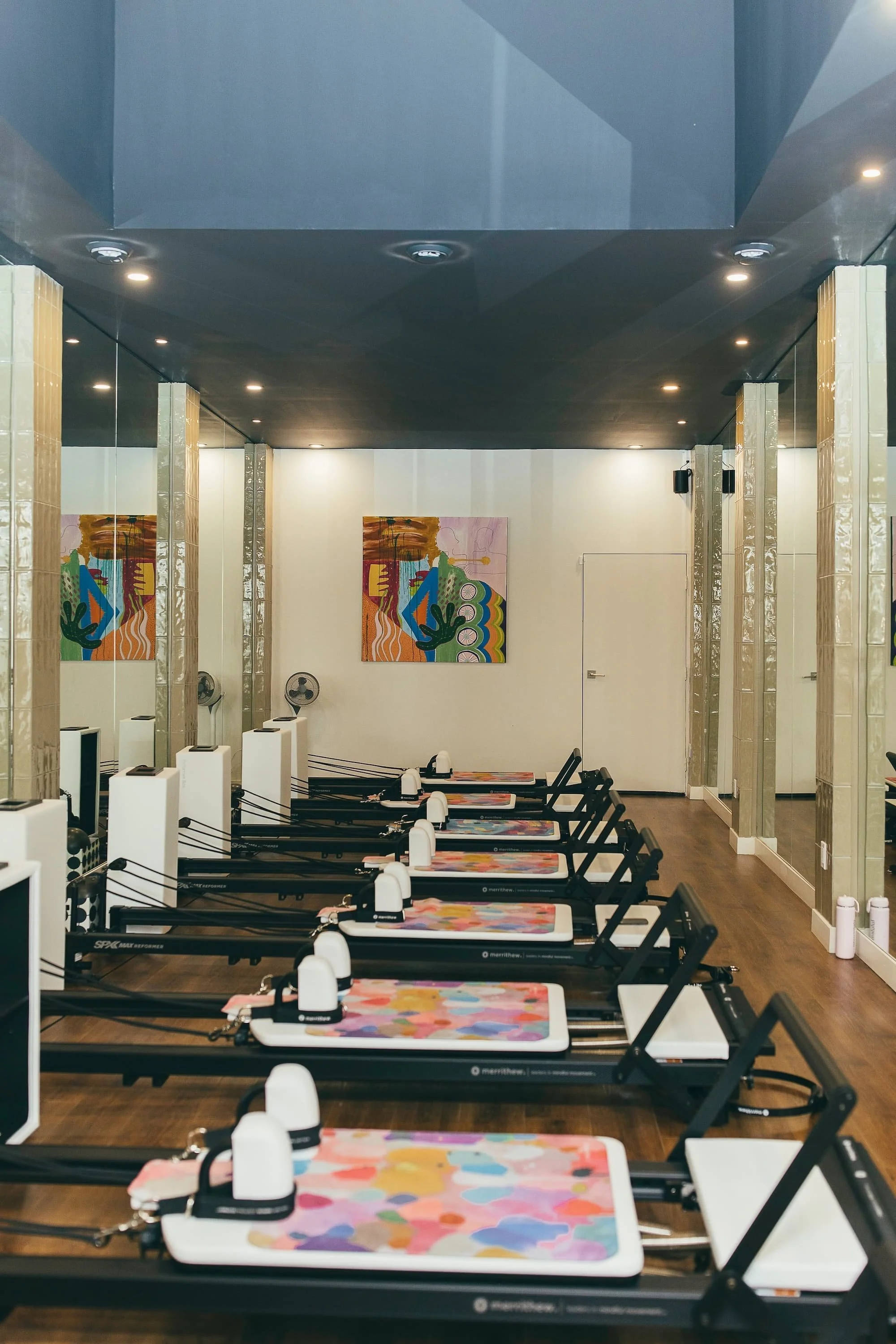 An empty pilates studio with a colorful painting on a white wall