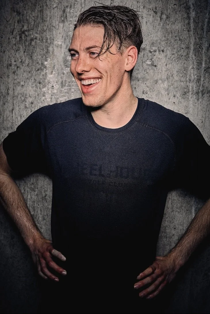 A woman smiles and looks to his right, hands on his hips