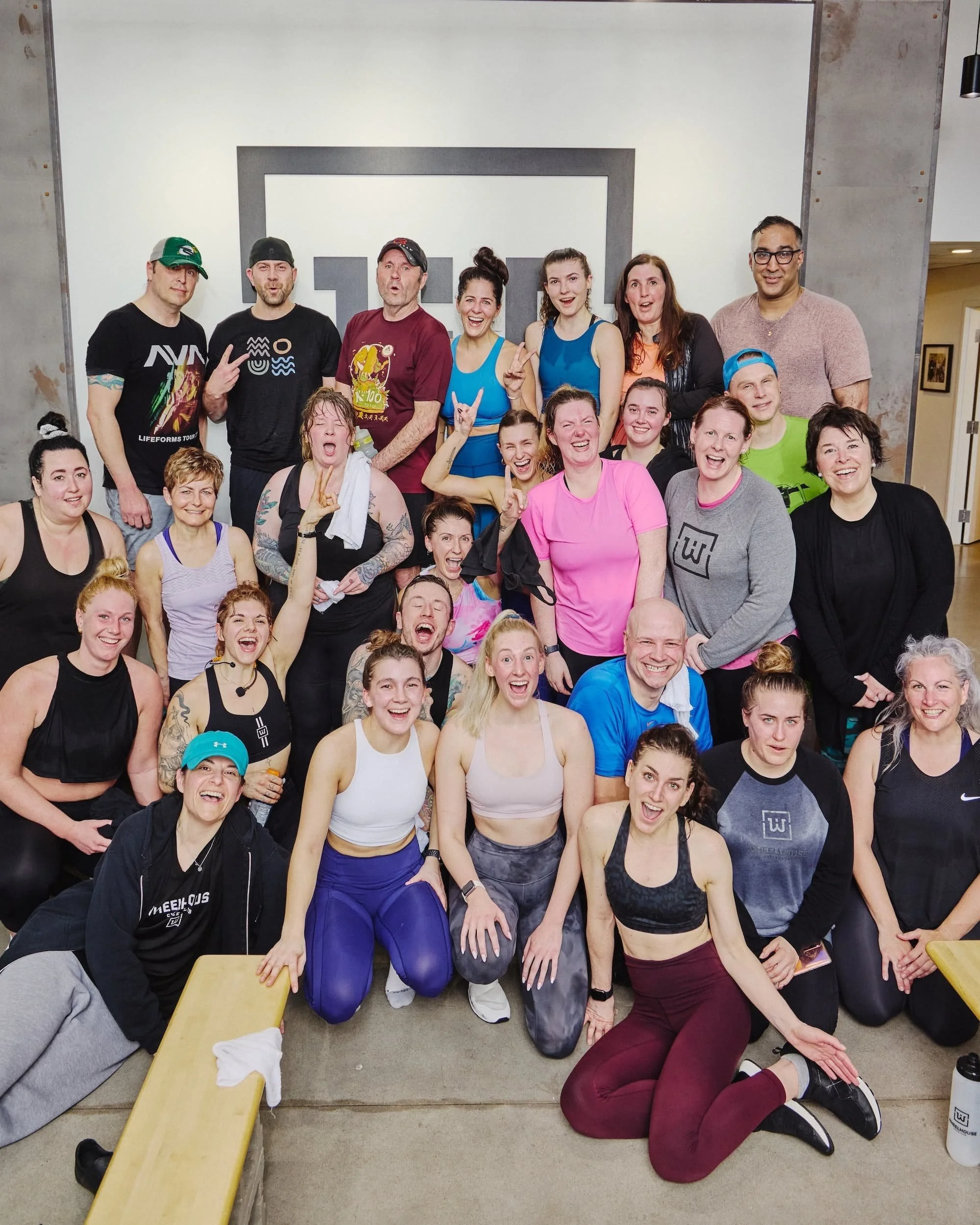 A group of people smile after an indoor cycling class