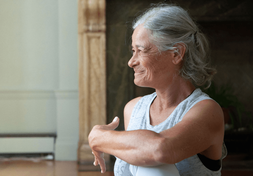 An older woman stretches, smiling with her eyes