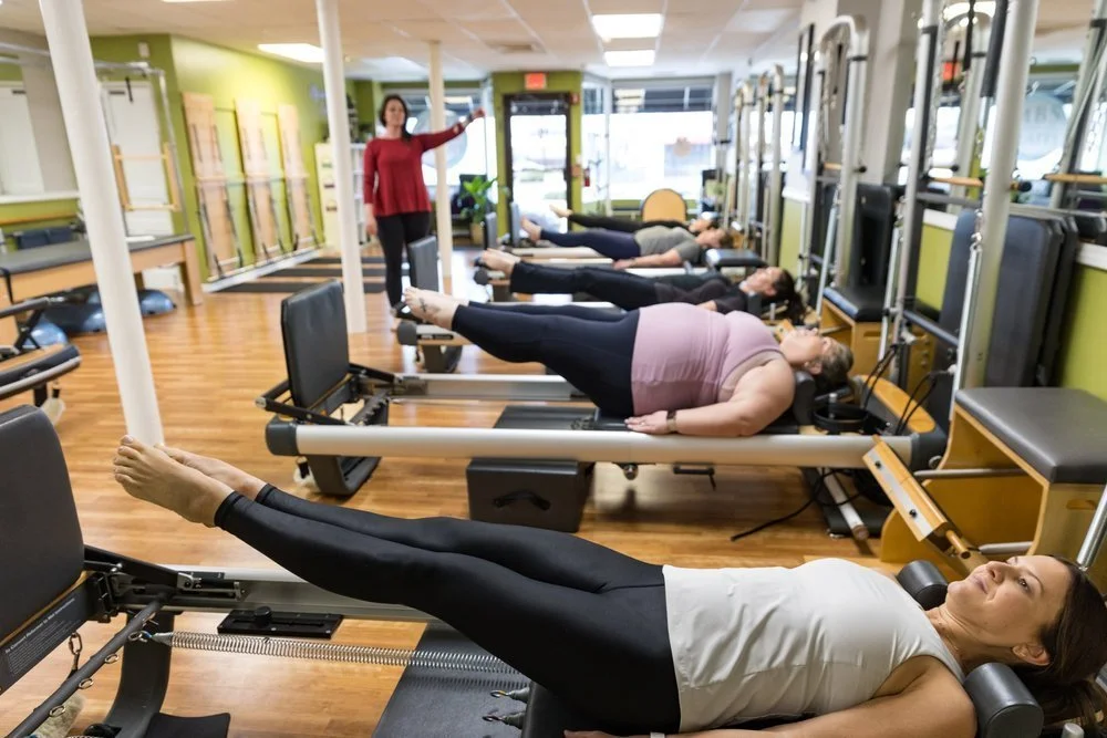 A row of studios exercises on pilates reformer machines