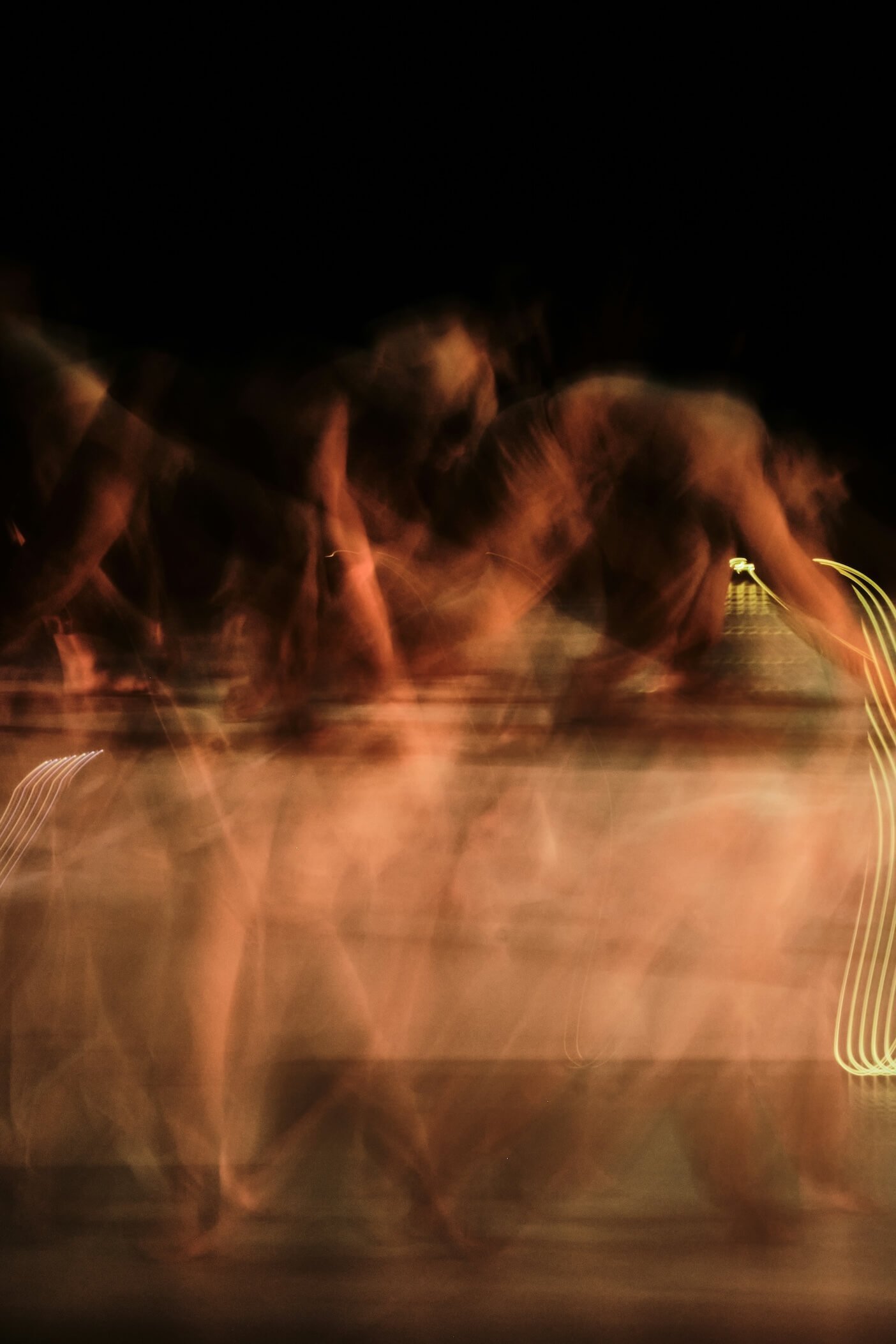 Blurred shapes walking through a scene with warm lighting, possibly at sunset or sunrise, with some light trails and motion effects.