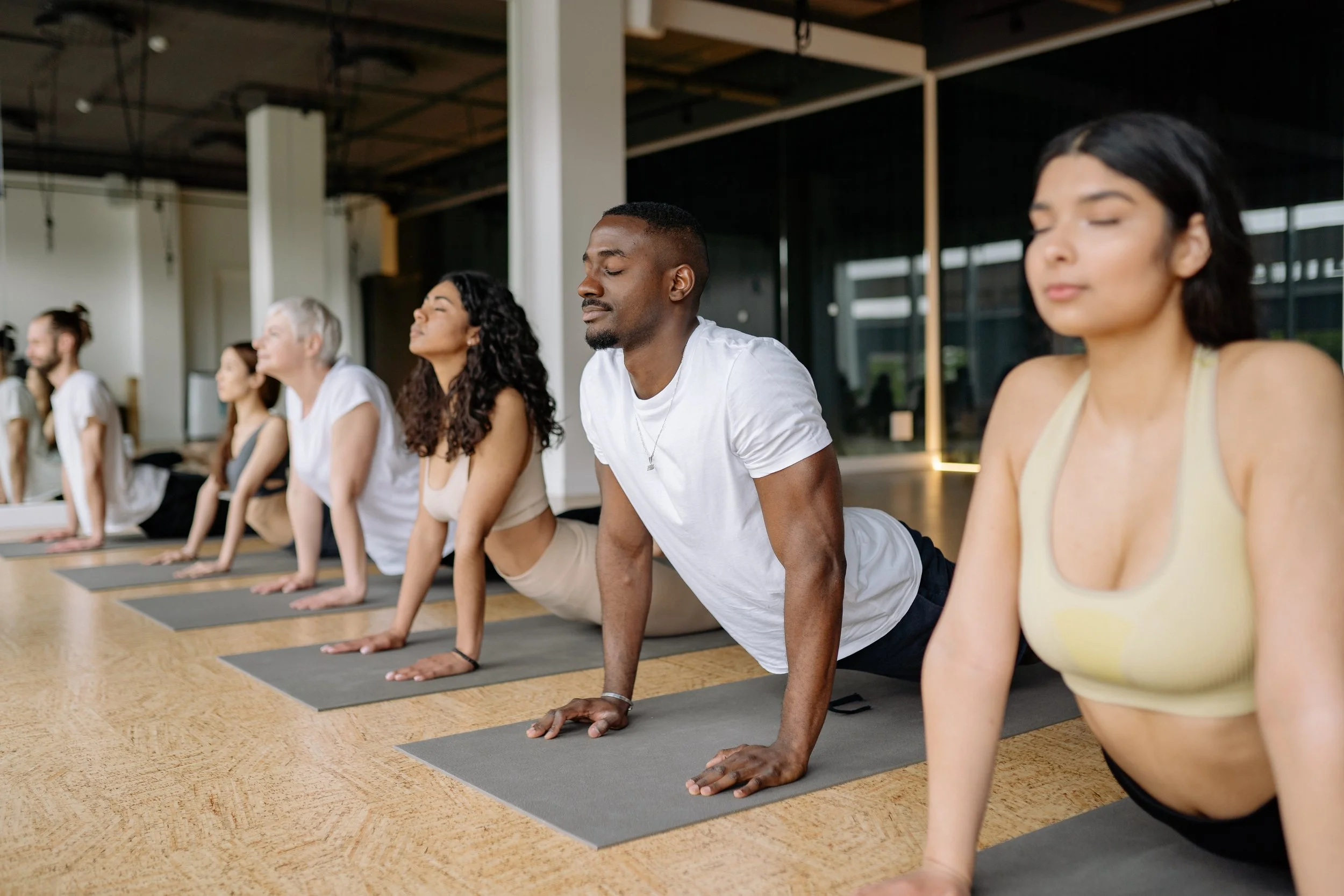 A group of people stretching during a mat yoga session