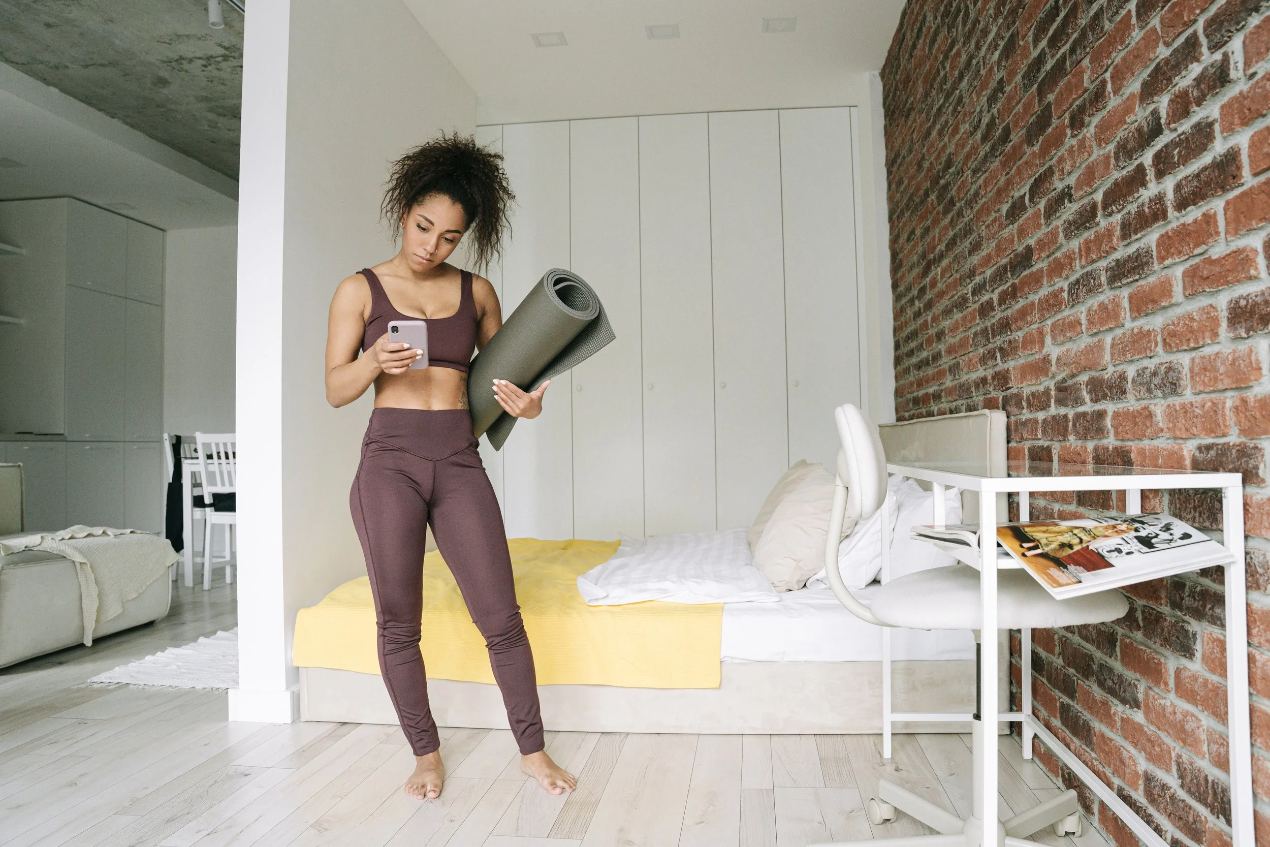 Woman holding a yoga mat while looking at her phone