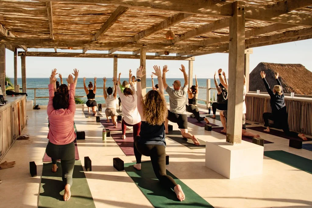 A group of people doing yoga during a wellnes retreat at Tulum, Mexico