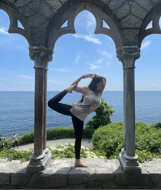 Woman performing an advanced yoga post in a picturesque castle while on a Treetop Yoga retreat.