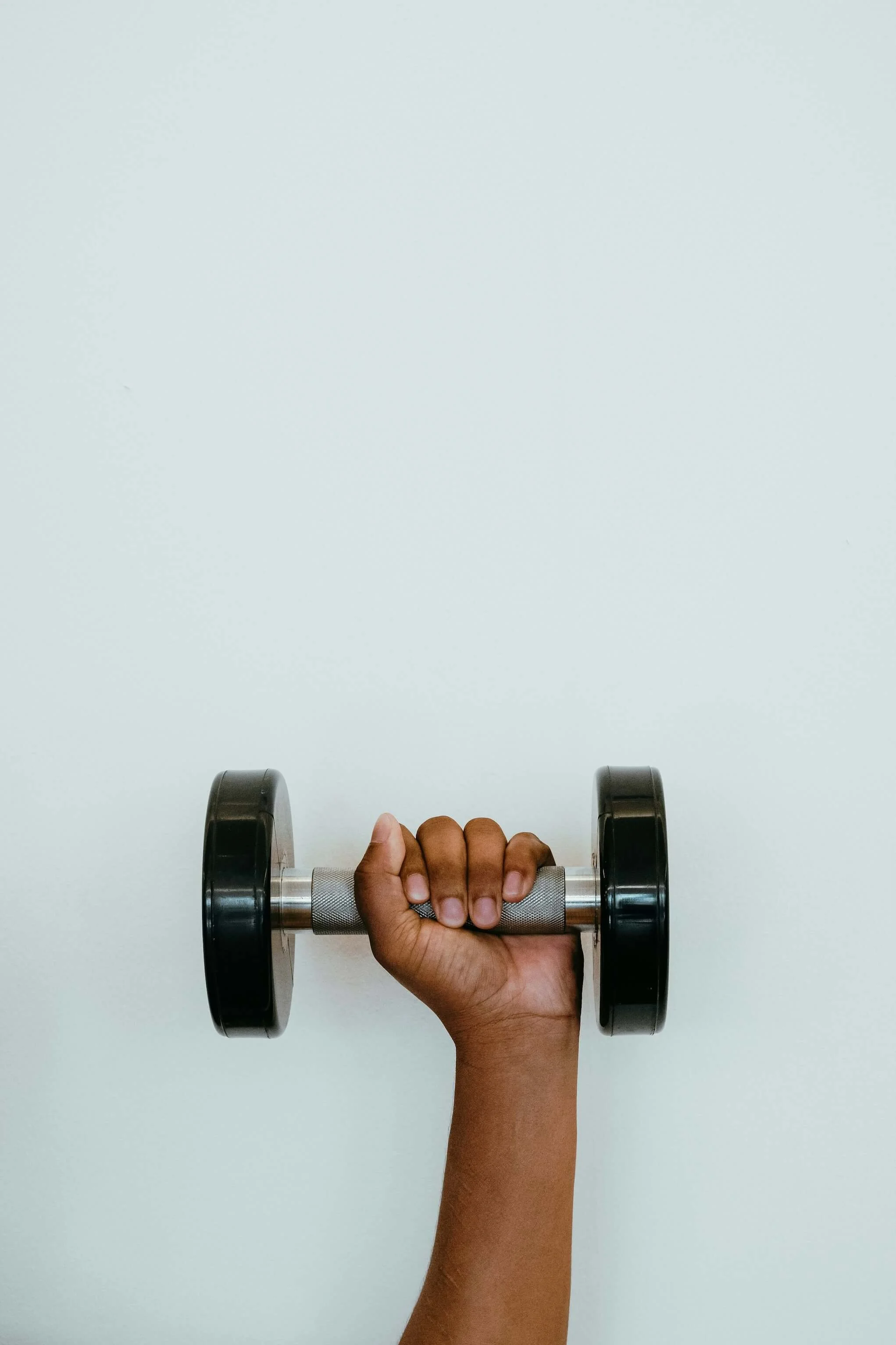 The hand of a Black woman holds up a dumbbell