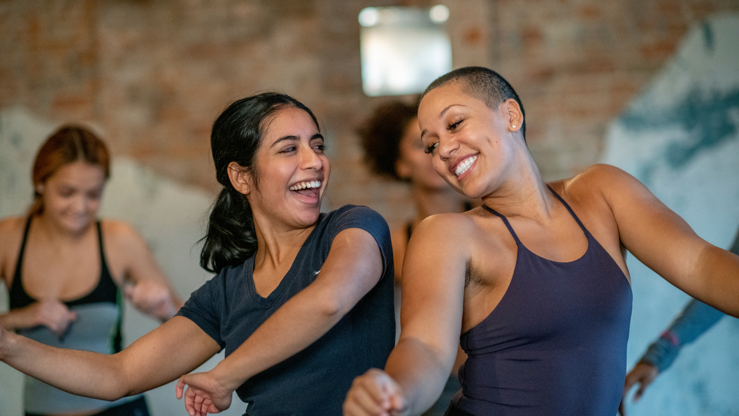 Two women dancing close to each other at a dance fitness class