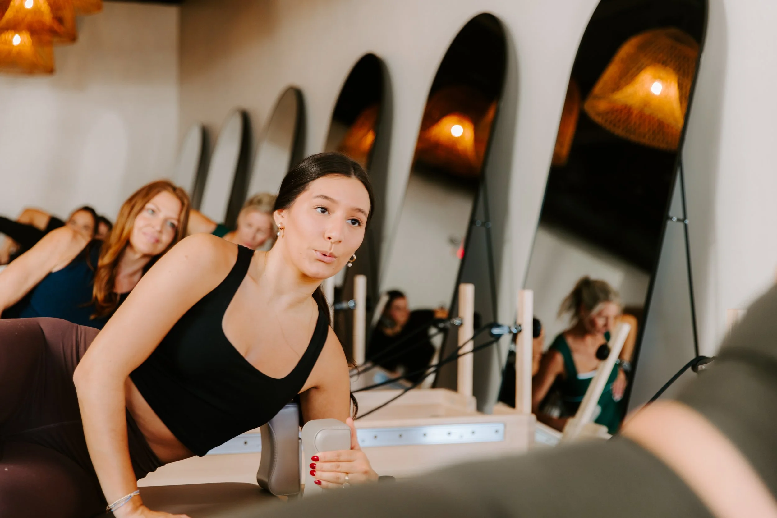 A group of women doing Pilates in a reformer studio