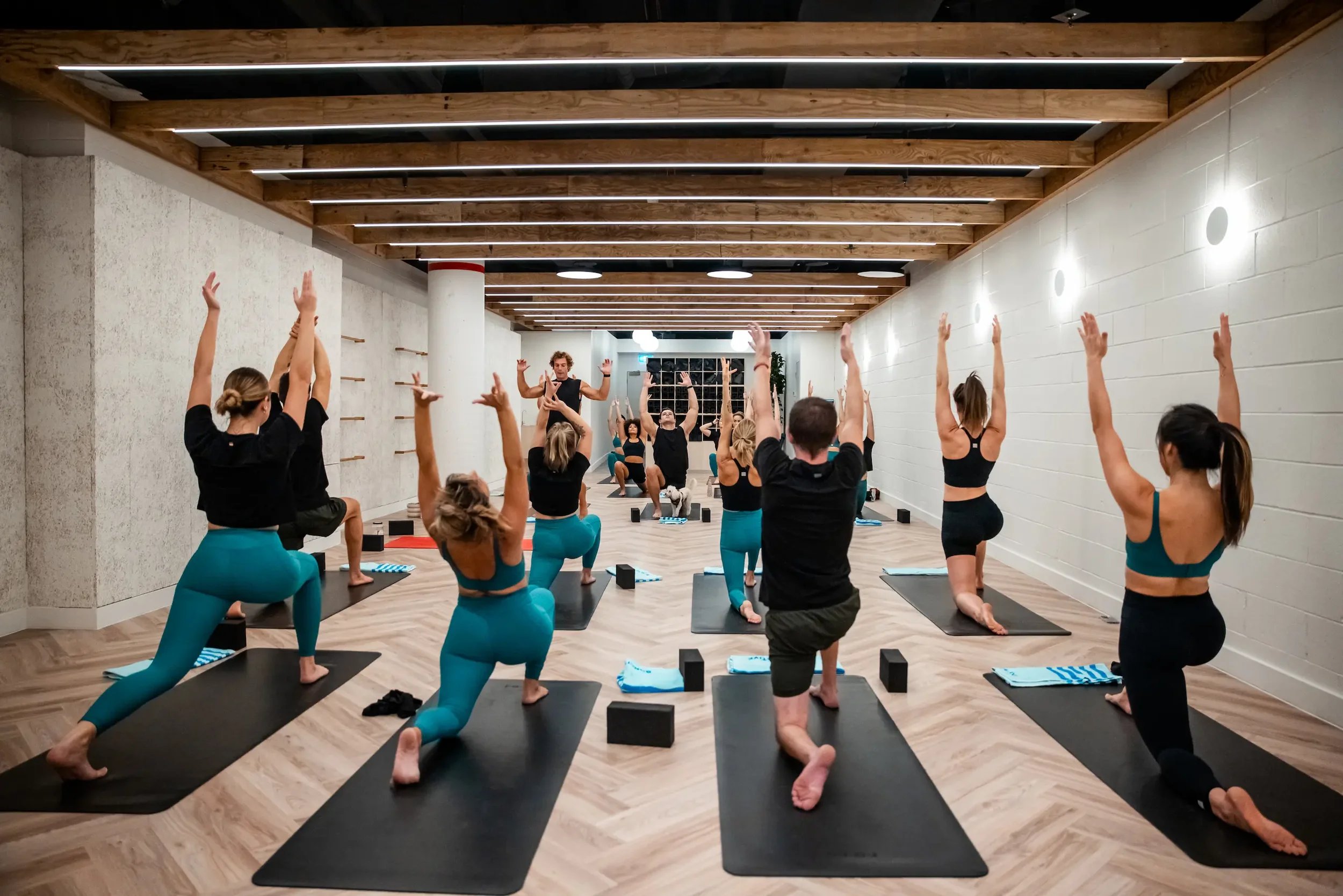 A group of people, all wearing workout sets in blue and black colors, as they're in a yoga class.