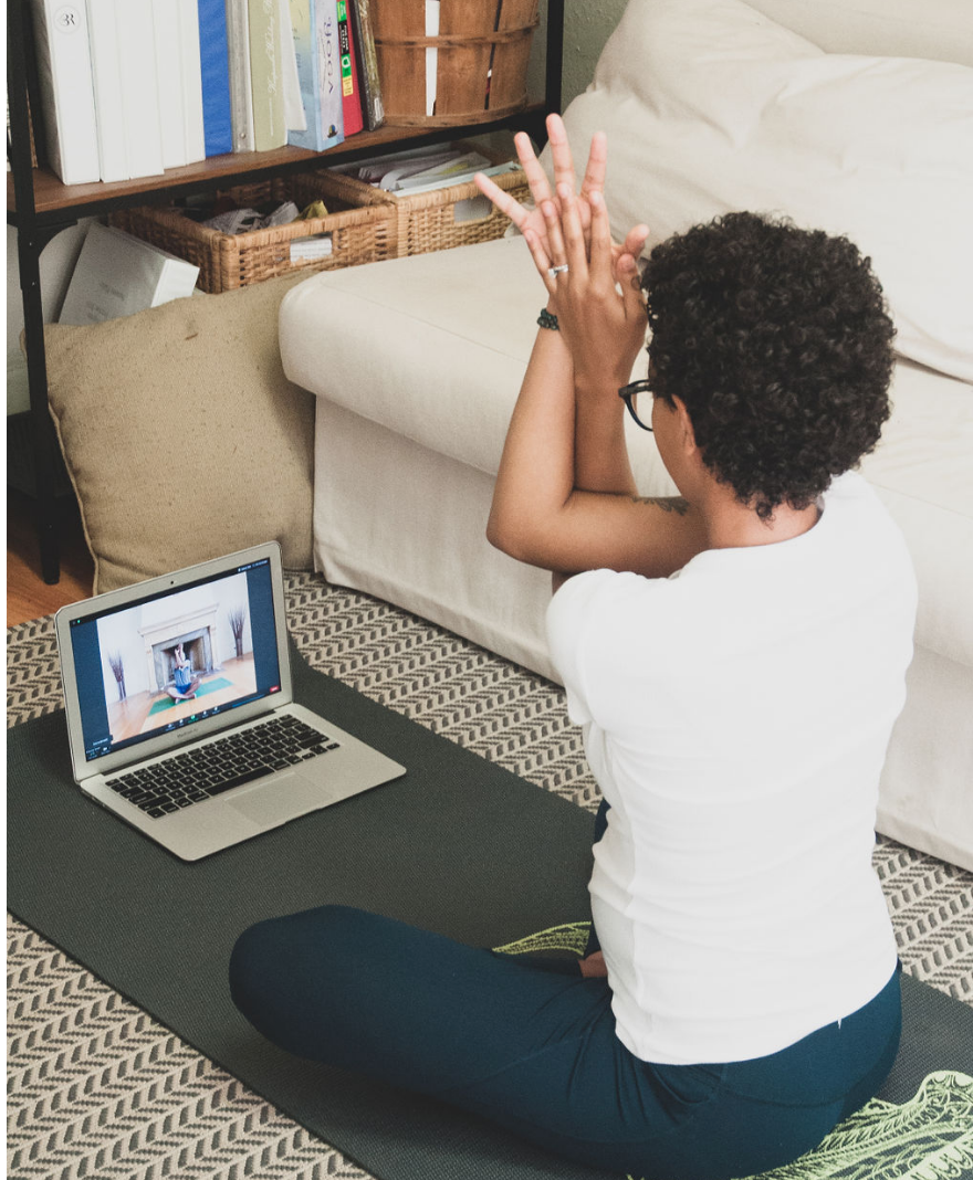 Woman doing yoga from home with ther laptop